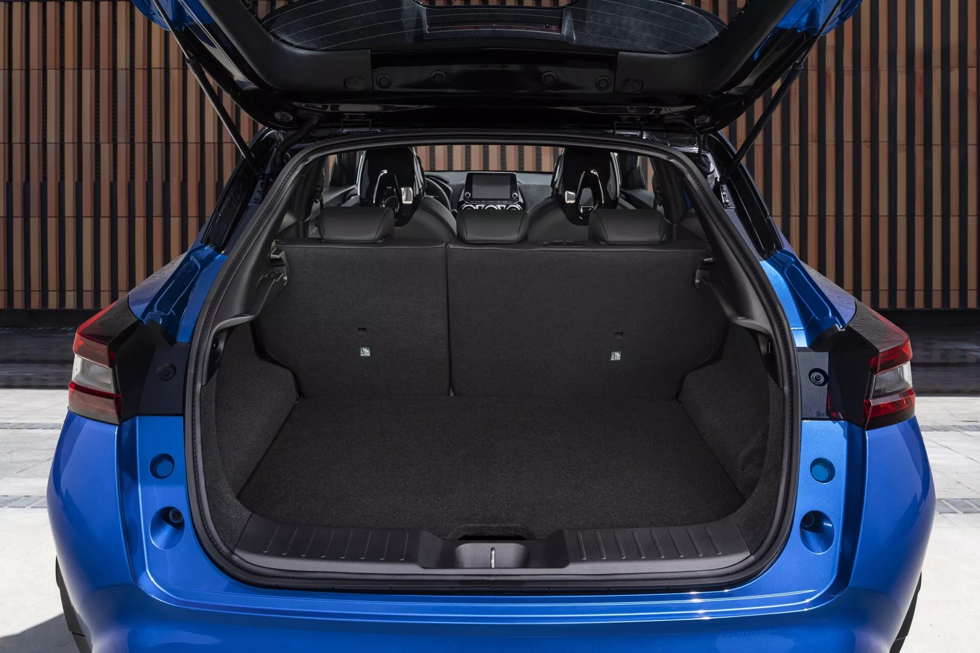 Vue arrière d'une Nissan Juke bleue 2019 F16 avec le coffre ouvert présentant l'espace de chargement et les caractéristiques de conception en plein jour