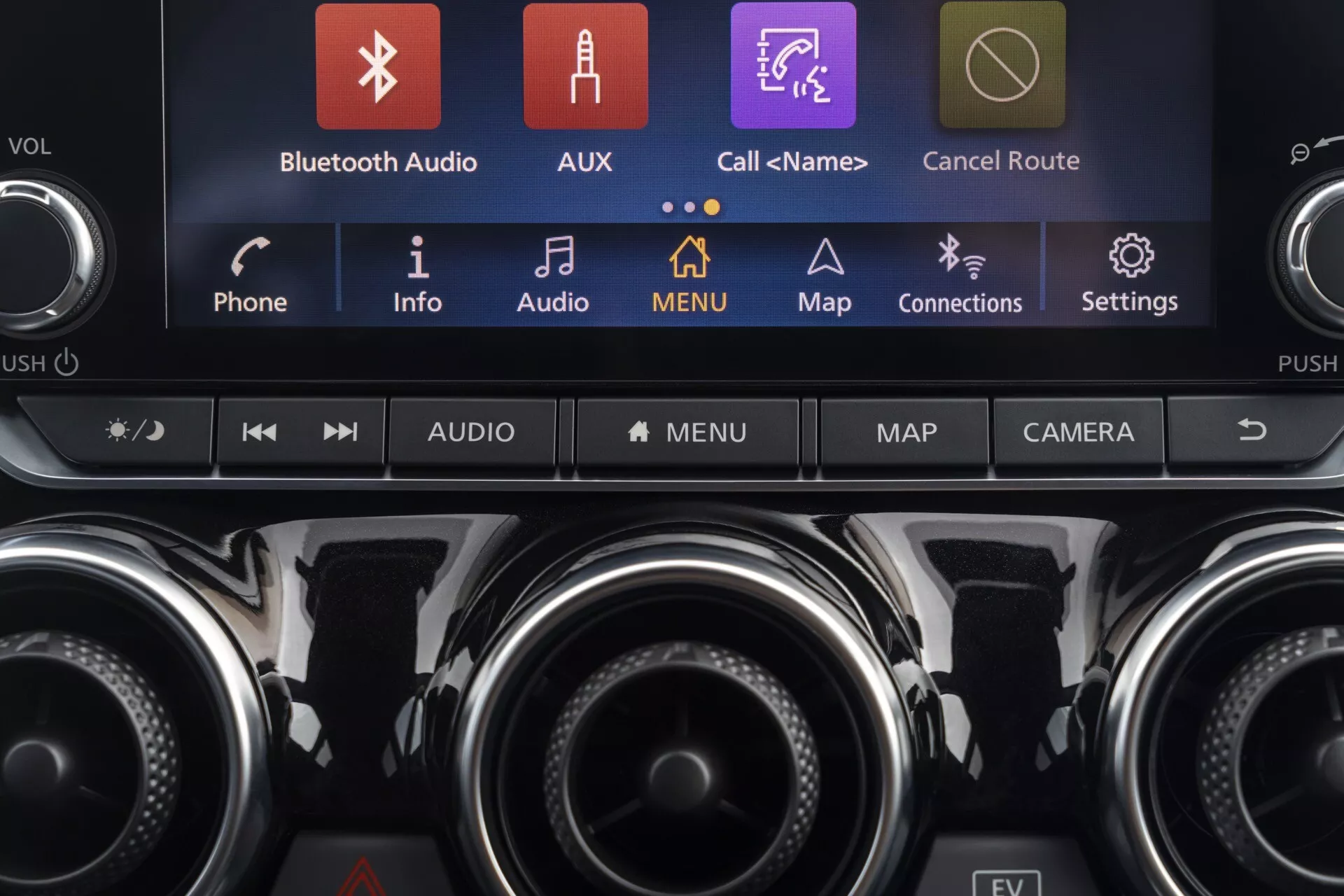 Vue détaillée de la console centrale de la Nissan Juke (F16) 2019 avec un système d’infodivertissement tactile affichant des icônes colorées telles que Bluetooth Audio, AUX et Cartes, accompagné de boutons de contrôle climatique et de fonctions supplémentaires, mettant en avant la technologie moderne du véhicule et le design intérieur premium