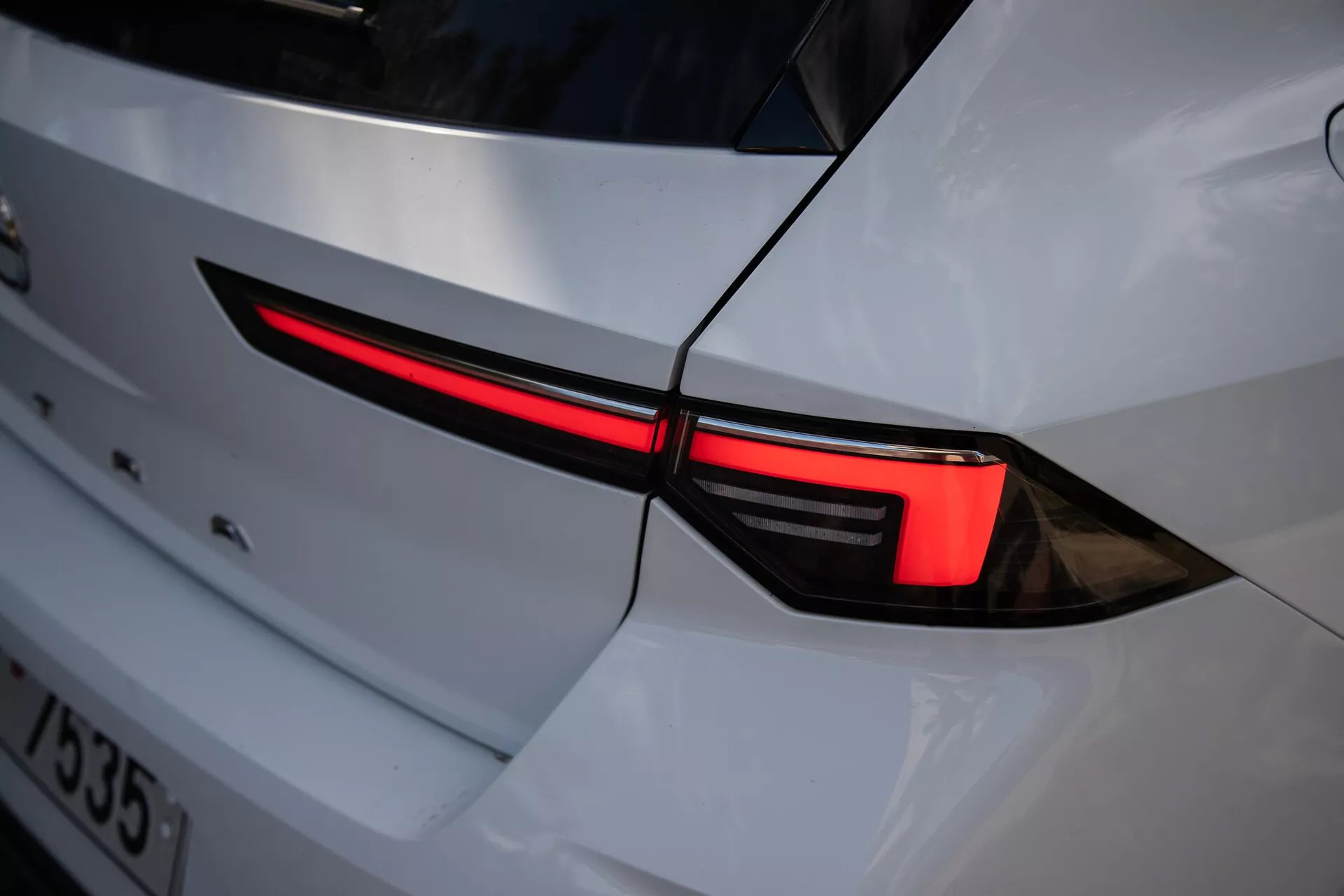 Gros plan sur le feu arrière gauche de l'Opel Astra 2022, mettant en avant un design LED élégant et son intégration dans la carrosserie blanche à l'esthétique sportive