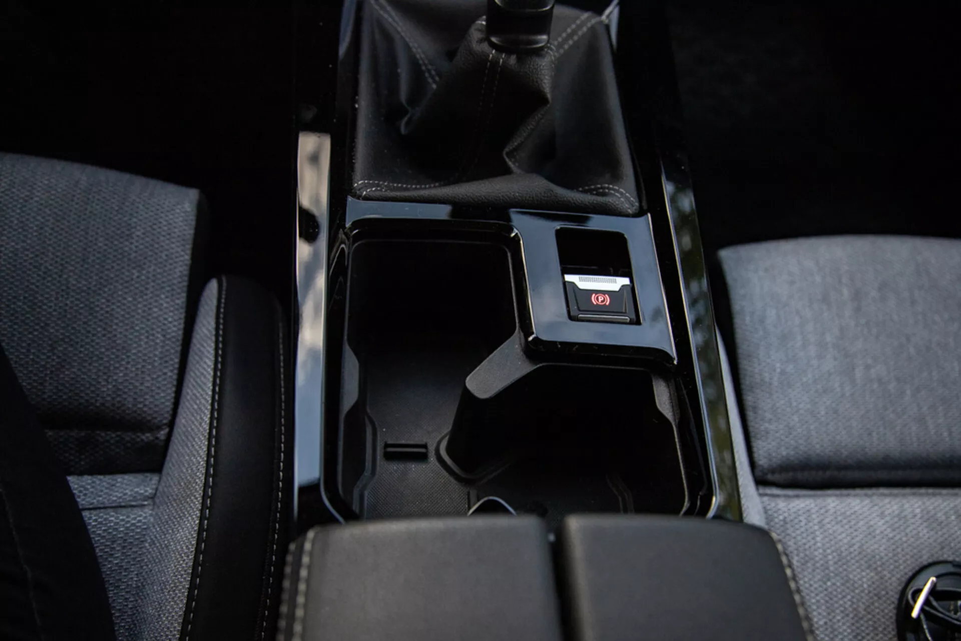 Détail de la console centrale de l'Opel Astra 2022 montrant un compartiment de rangement ouvert, une garniture en tissu, un levier de vitesse manuel en cuir perforé, un port USB et un éclairage intérieur