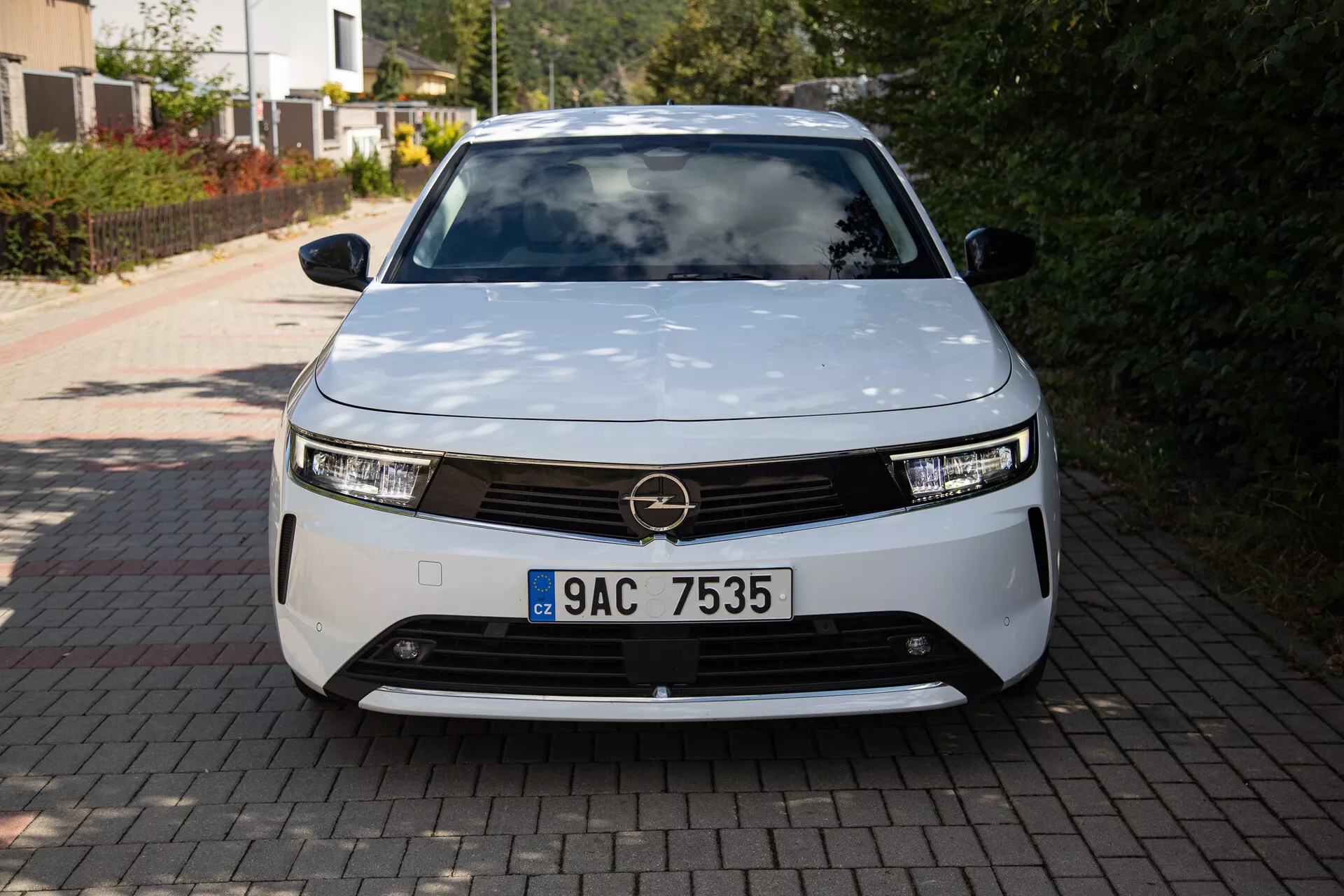 Vue de face de l'Opel Astra 2022 présentant un design moderne de véhicule électrique avec phares à LED, grille décorative et forme aérodynamique, garée sur une allée résidentielle