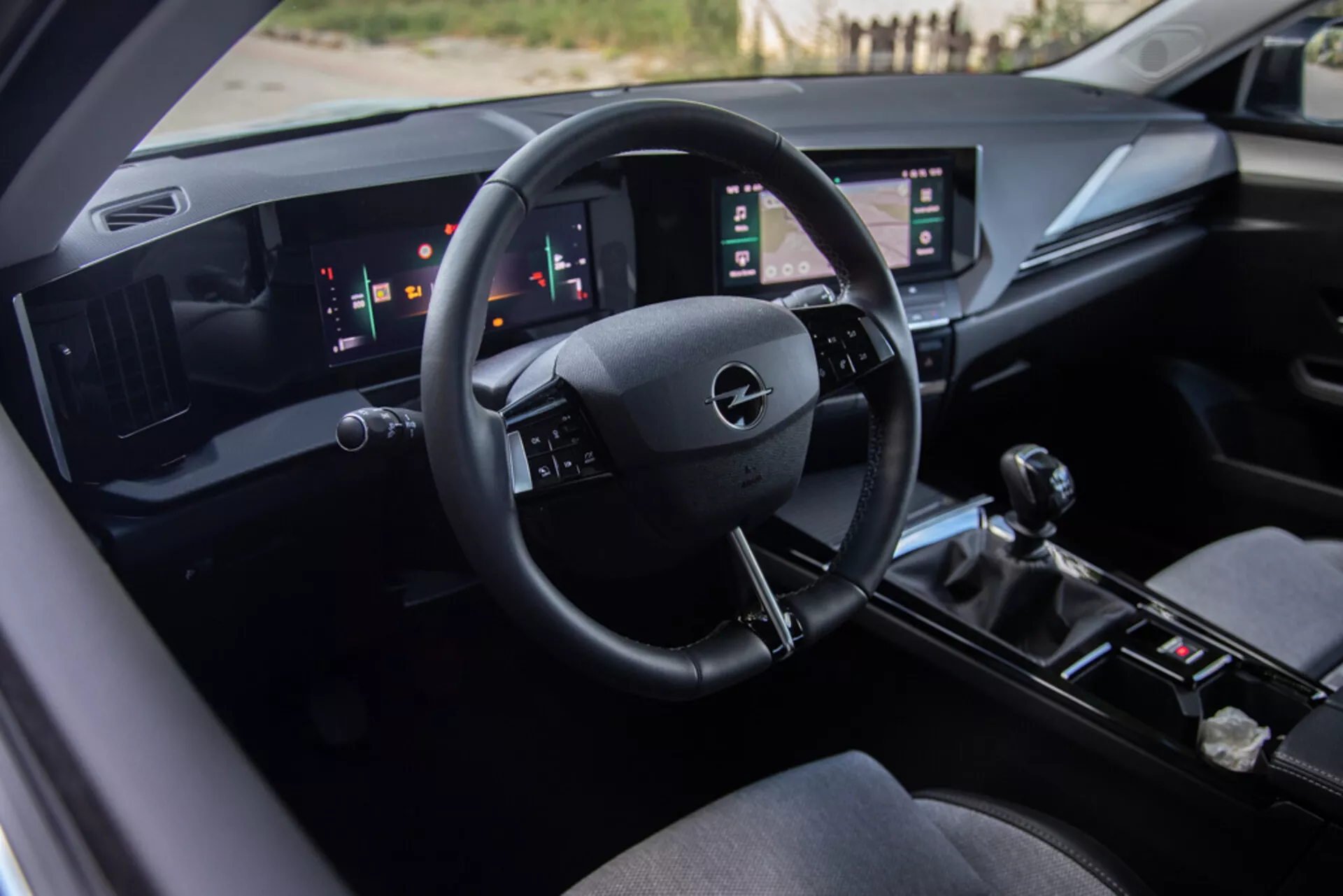 Intérieur de l'Opel Astra 2022 mettant en vedette le siège conducteur, un tableau de bord technologiquement avancé avec le logo Opel sur le volant, des jauges numériques et des panneaux tactiles verticaux doubles
