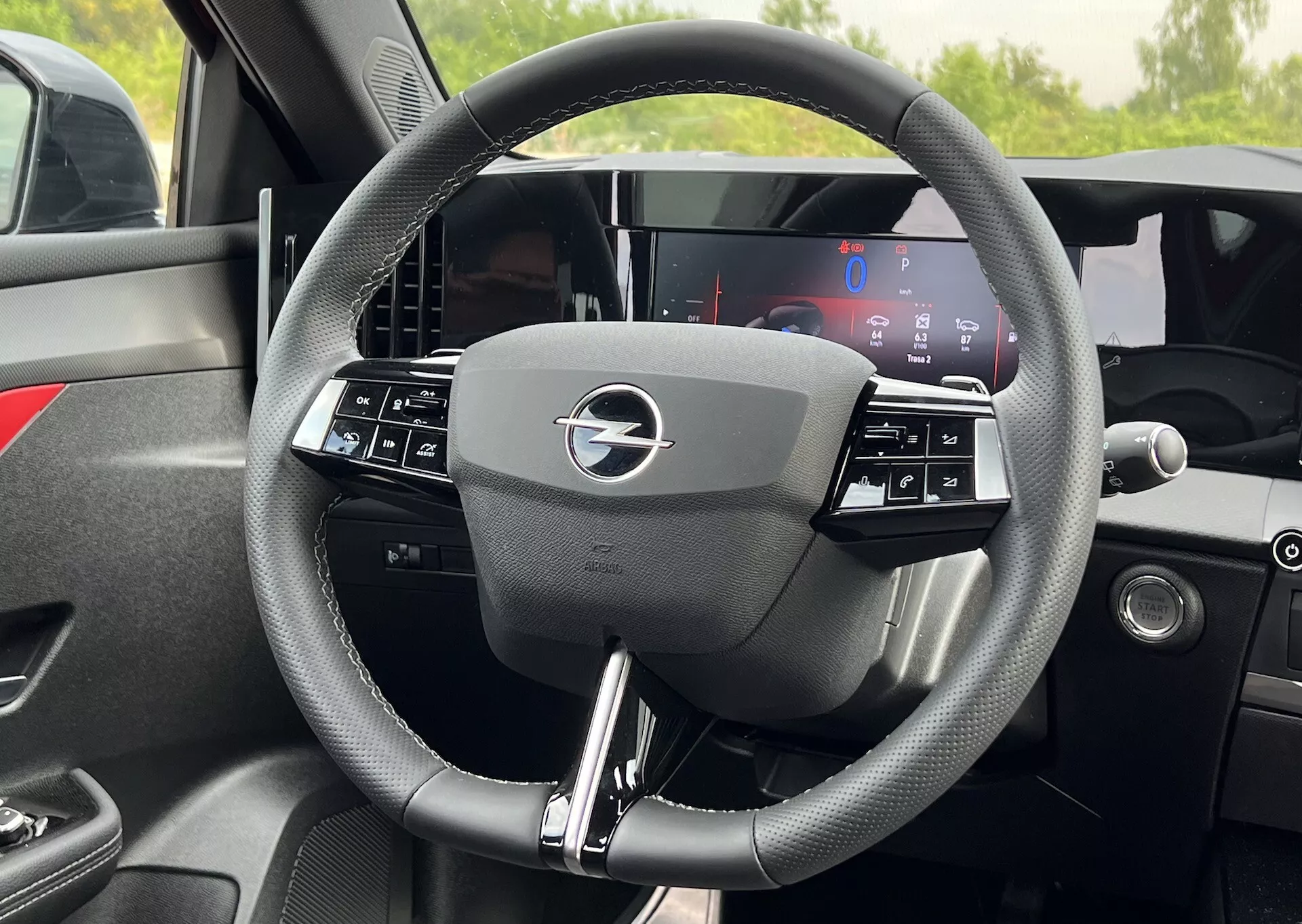 Vue intérieure détaillée du volant de l'Opel Astra 2022 avec design à trois branches intégrant des commandes et un tableau de bord entièrement numérique derrière, mettant en avant la technologie moderne et l'ergonomie du véhicule