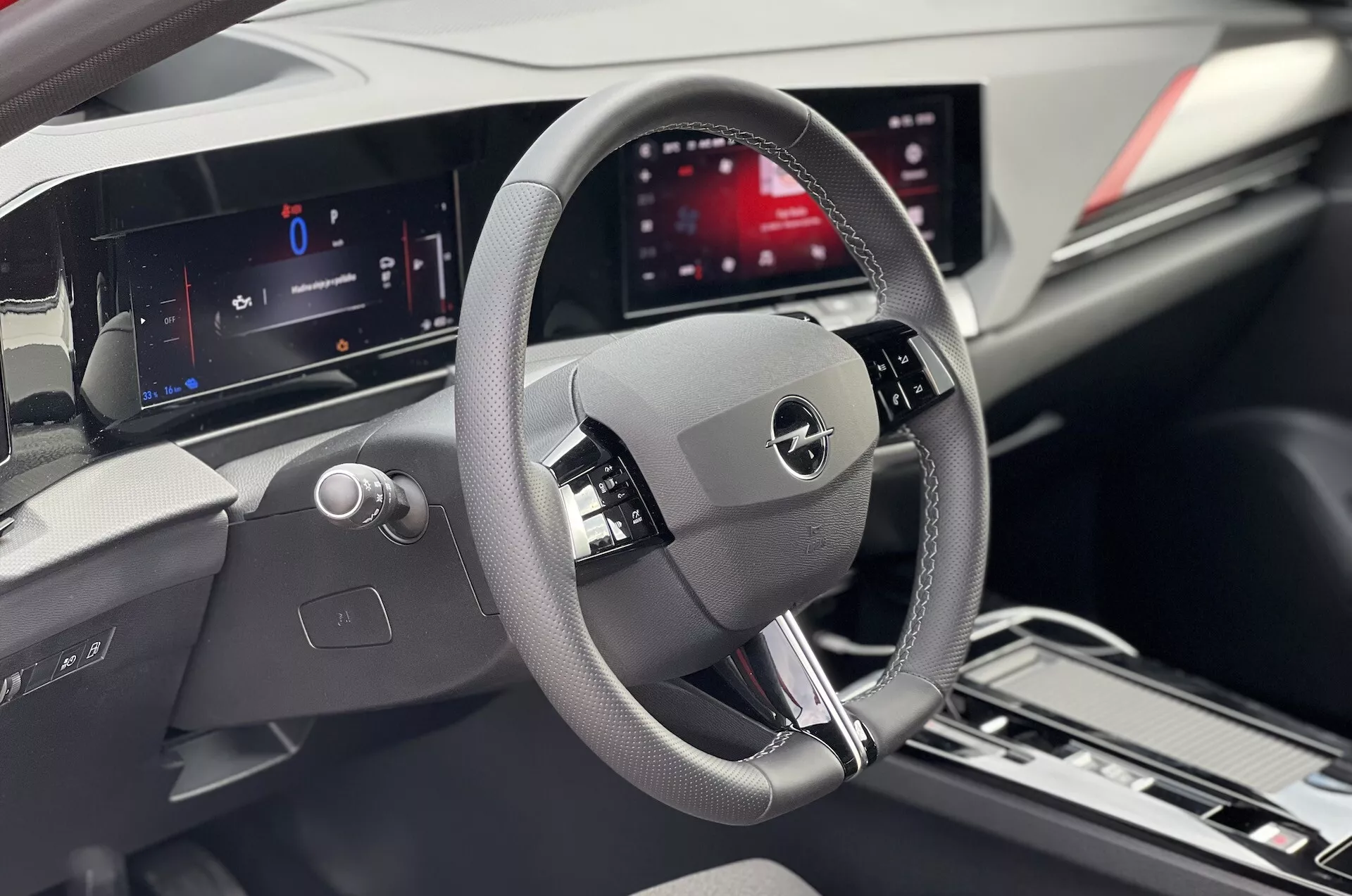 Vue intérieure d'une Opel Astra 2022 focalisée sur la zone du conducteur avec volant détaillé, tableau de bord numérique et affichage central d'infodivertissement