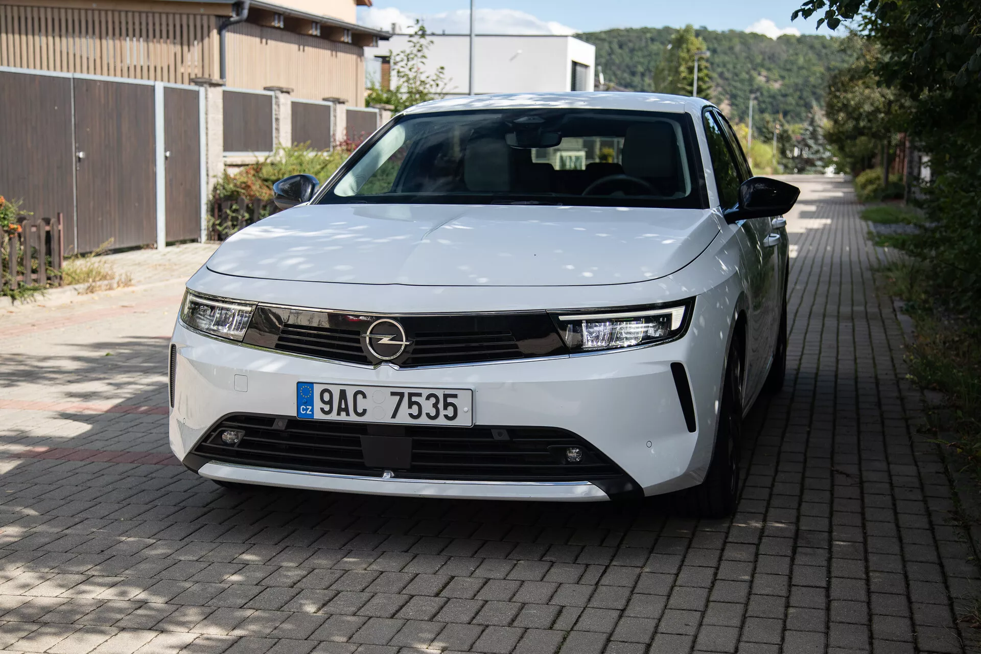 Vue avant trois-quarts de l'Opel Astra 2022 mettant en évidence les phares LED, le design minimaliste de la grille, les jantes en alliage partiellement visibles et les panneaux de carrosserie élégants dans une rue résidentielle européenne