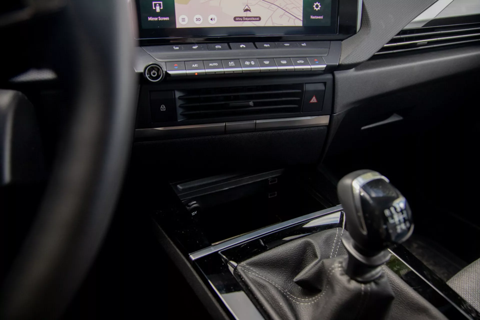 Vue intérieure de l'Opel Astra 2022 centrée sur la console centrale et le levier de vitesses manuel du point de vue du conducteur, avec volant, éléments de design de luxe et système d'infodivertissement moderne.