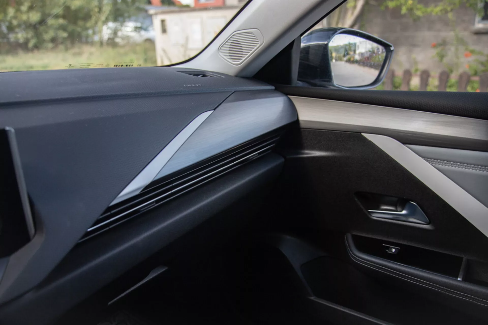 Vue intérieure depuis le siège passager montrant la conception du tableau de bord, garnitures et panneau de porte dans une Opel Astra 2022, avec des lignes contourées sombres et élégantes se concentrant sur la texture des matériaux et les intégrations technologiques potentielles