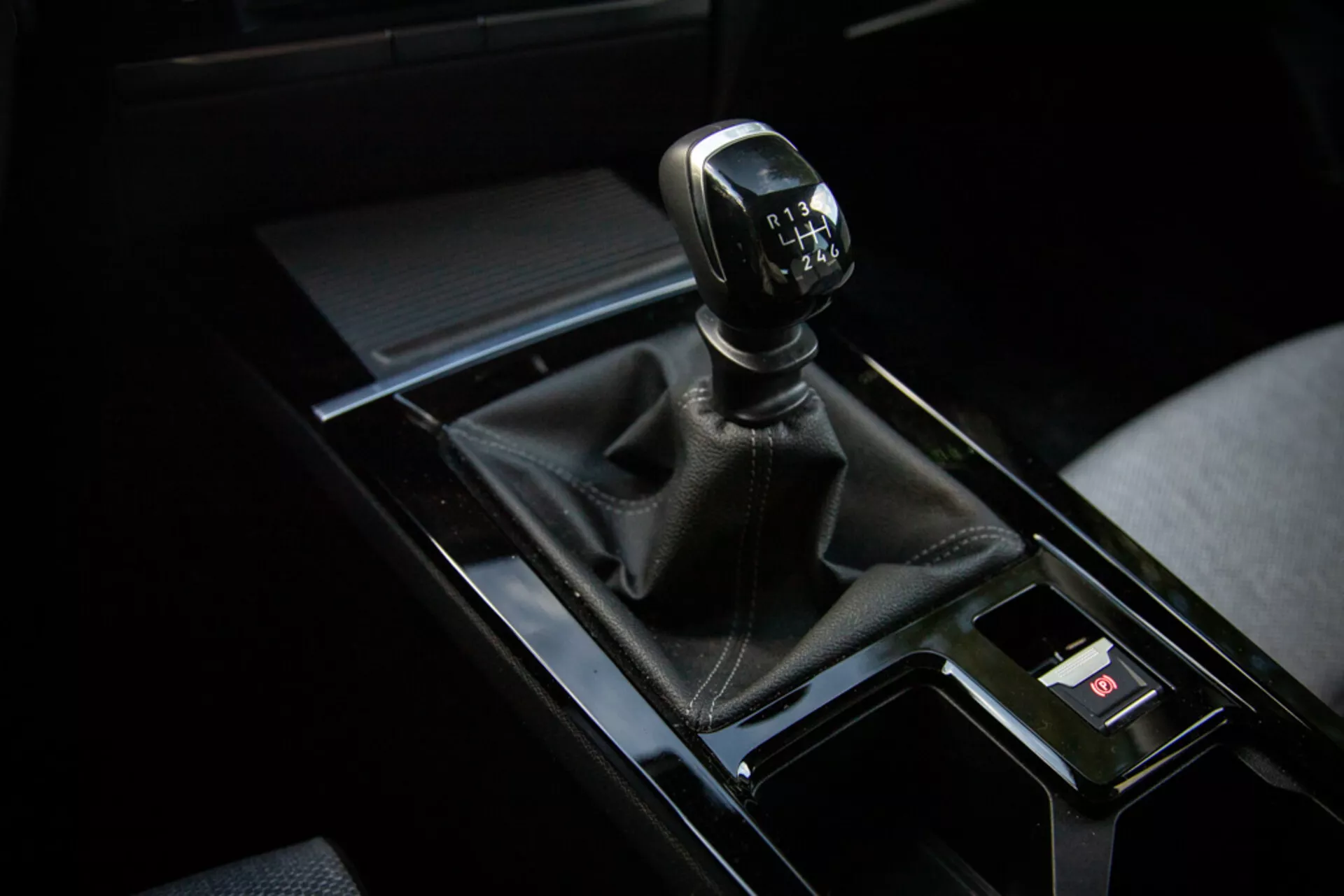 Gros plan sur le levier de vitesse manuelle de l'Opel Astra 2022 dans le quadrant supérieur droit avec botte en cuir, console noire brillante et éléments intérieurs environnants
