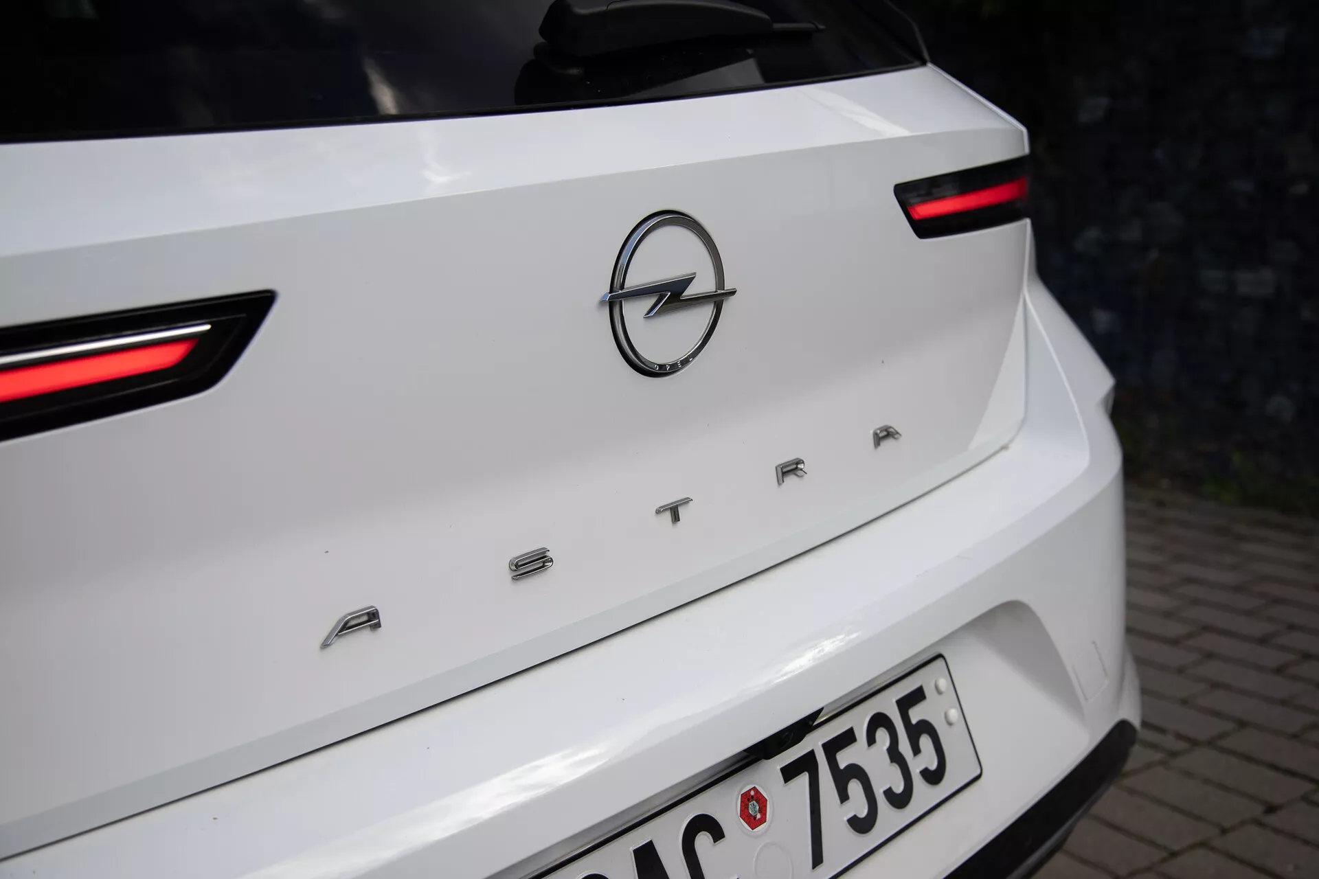 Vue rapprochée de l'arrière d'une Opel Astra blanche de 2022, mettant en lumière les feux arrière LED, le logo Opel et le nom du modèle 'ASTRA' sur le couvercle du coffre