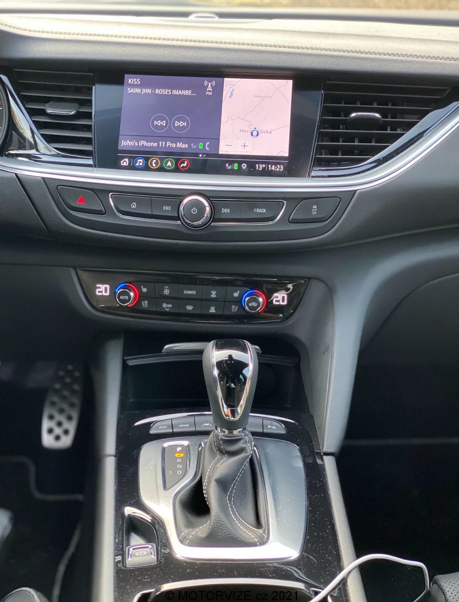 Vue intérieure de l'Opel Insignia 2020 centrée sur la console centrale et le tableau de bord, montrant l'écran d'infodivertissement avec navigation et multimédia, commandes de climatisation bizone, levier de vitesses automatique avec sélecteur de mode de conduite et boutons pour différentes fonctions, le tout dans un mélange de plastique doux et de finitions décoratives.