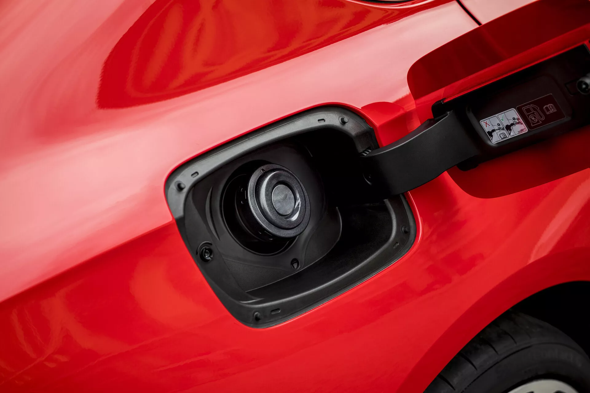 Gros plan sur le port de charge d'une Opel Insignia 2013 mettant en évidence sa capacité électrique ou hybride avec une vue détaillée de la porte du port de charge ouverte et de la prise contre la carrosserie rouge du véhicule