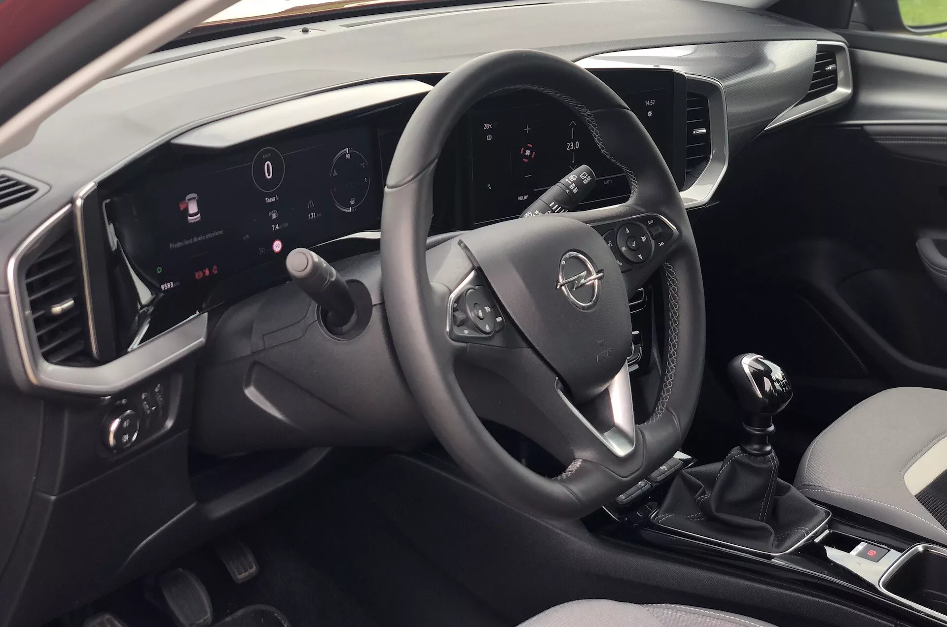 Vue intérieure de l'Opel Mokka 2021 depuis la perspective d'un passager arrière à droite, dévoilant le tableau de bord moderne, le volant multifonctions, le tableau de bord numérique éclairé, le système d'infodivertissement à écran tactile, le levier de vitesse manuel et le design élégant bicolore.