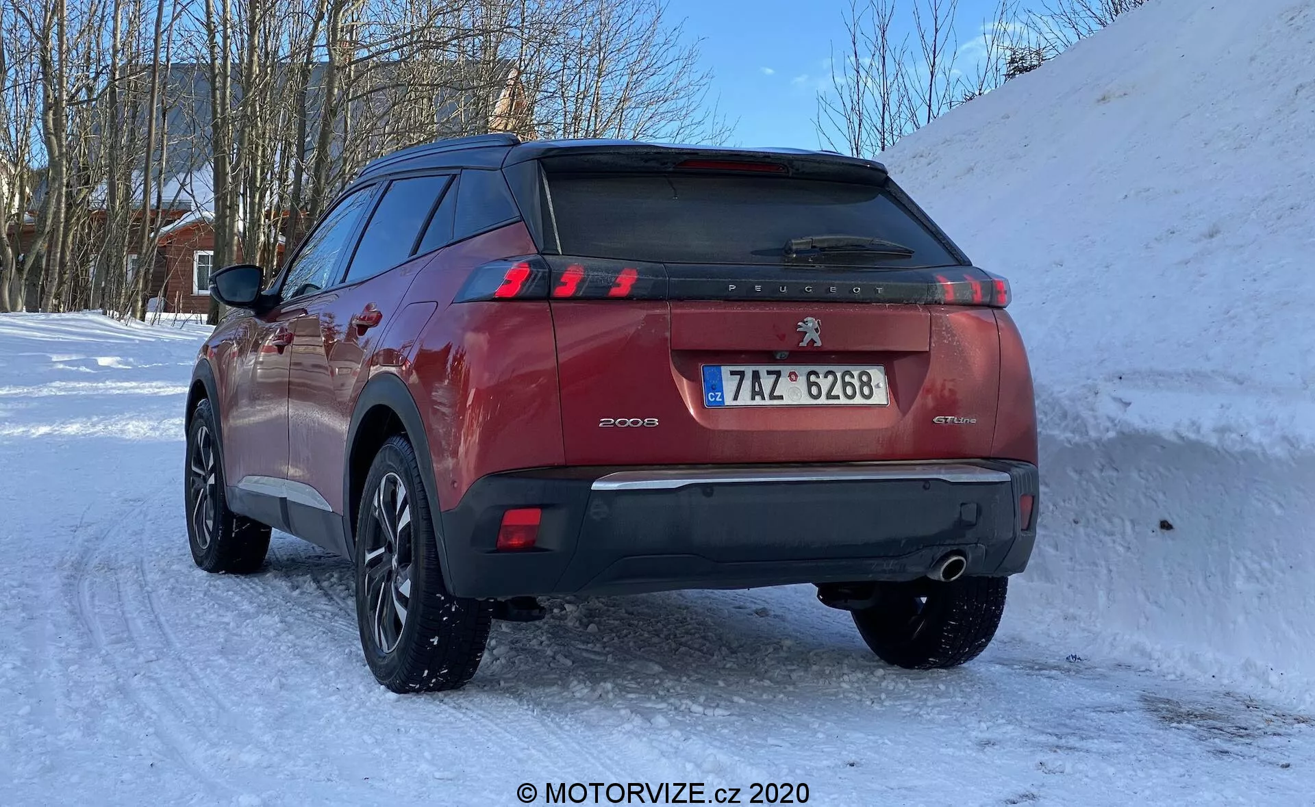 SUV Peugeot 2008 1.2 PureTech 100 Active 2020 dans un cadre hivernal enneigé, vue de trois quarts arrière mettant en valeur le hayon, les feux arrière à LED en forme de griffes, les capteurs de stationnement sur le pare-chocs arrière, le double échappement, la plaque d'immatriculation de style européen et les jantes en alliage multi-rayons avec pneus hiver.