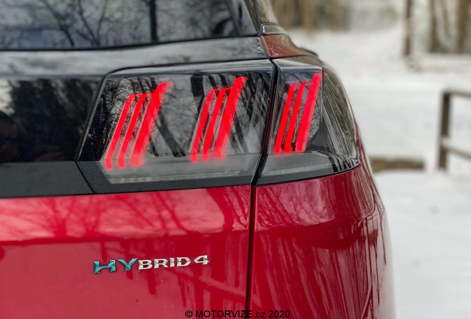 Peugeot 3008 Hybrid4 2021 - Vue de l'angle arrière gauche en gros plan, montrant la peinture rouge vibrante, ensemble des feux arrière à LED rouges modernes avec segments verticaux distincts, le couvercle du coffre et le badge hybride sur le coin arrière gauche, indiquant un système de propulsion hybride avec une possible transmission intégrale.