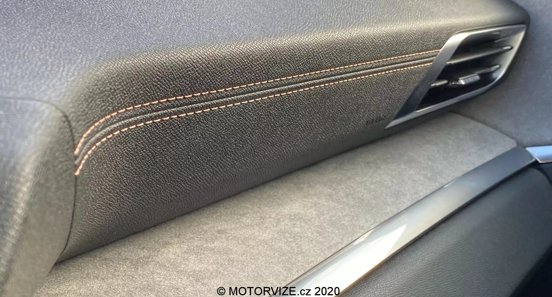 Gros plan de l'intérieur de la porte de la Peugeot 3008 2021, mettant en évidence la convergence de l'accoudoir texturé en cuir avec des coutures contrastées et de la poignée de porte métallique. Les accents argentés suggèrent un souci de l'artisanat et de la qualité des matériaux, avec des ombres indiquant une source de lumière intérieure.
