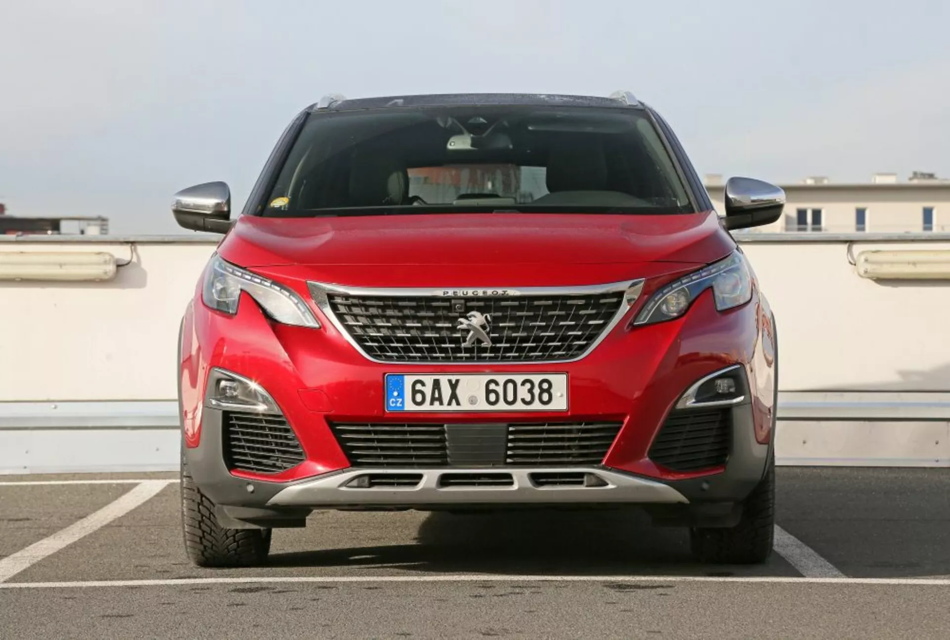 Vue de face d'une Peugeot 3008 rouge de 2016 avec grille et emblème chromés, phares avant LED modernes et éléments de conception aérodynamique, photographiée en extérieur