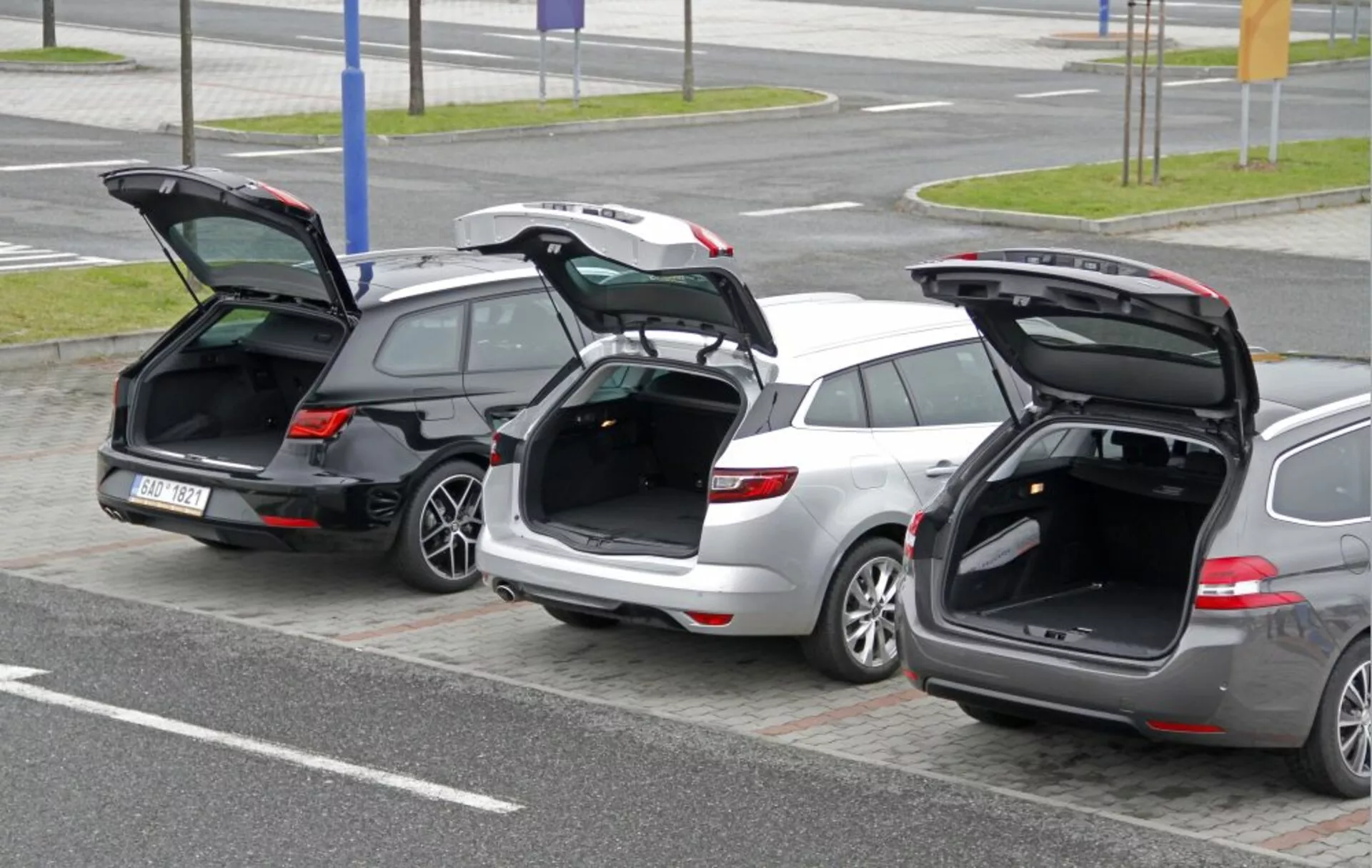 Trois breaks Peugeot 308 SW 2013 garés côte à côte avec les hayons arrière ouverts mettant en évidence l'espace de chargement et la conception du hayon depuis un angle élevé