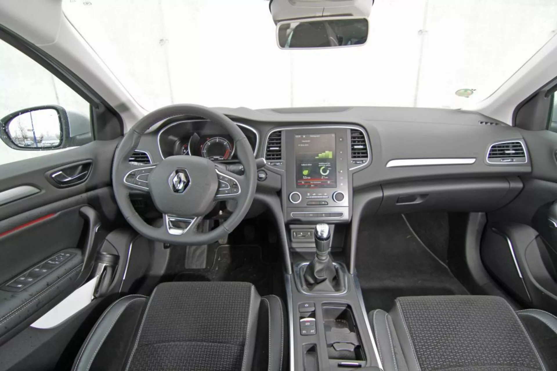 Vue intérieure de la Peugeot 308 SW de 2013 depuis le siège arrière central montrant le tableau de bord, le volant avec boutons multifonctions, le cluster d'instruments, la console centrale avec écran d'infodivertissement, le levier de vitesse automatique, les commandes de climatisation, les sièges baquets avant en tissu, les panneaux de porte avec commandes, les rétroviseurs latéraux, le toit de la voiture, le rétroviseur, et le schéma de couleurs sombres moderne avec des accents argentés