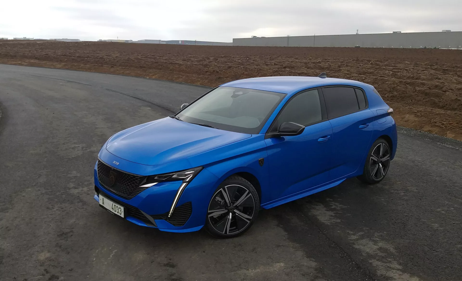 Peugeot 308 hatchback 2022 en bleu vif, présentant un design aérodynamique, des phares LED, une grille avant avancée, des roues en alliage à multiples rayons et des caractéristiques de sécurité modernes, stationnée sur le tarmac