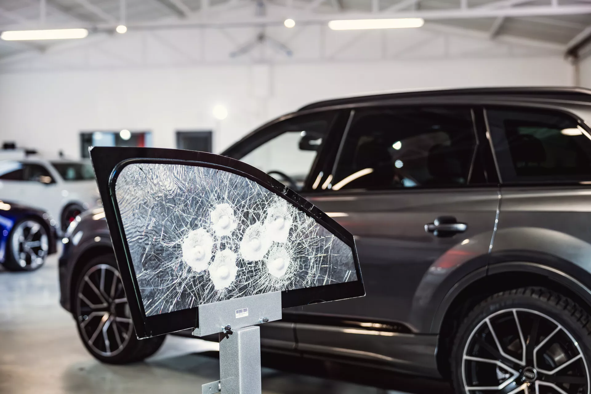 Peugeot 308 2022 exposée dans un showroom avec focus sur un affichage de verre brisé ressemblant à un miroir latéral au premier plan, suggérant des caractéristiques de sécurité ou des tests de durabilité, et montrant le profil latéral élégant de la voiture avec des caractéristiques de SUV moderne en arrière-plan
