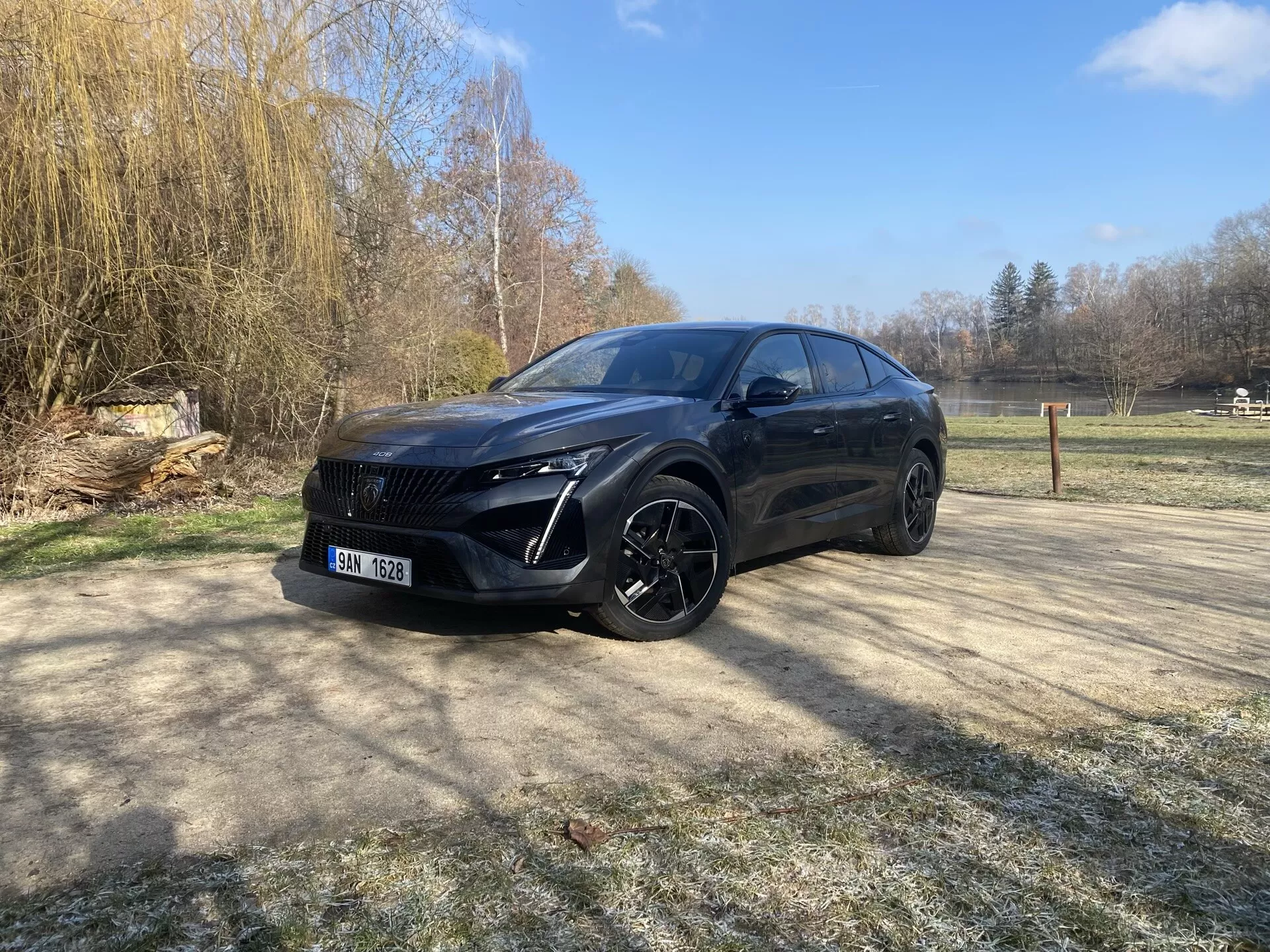 Peugeot 408 de 2023 garée en extérieur pendant la journée avec un ciel dégagé, mettant en avant des phares LED, une grille avant proéminente, de grandes roues en alliage et un design crossover moderne