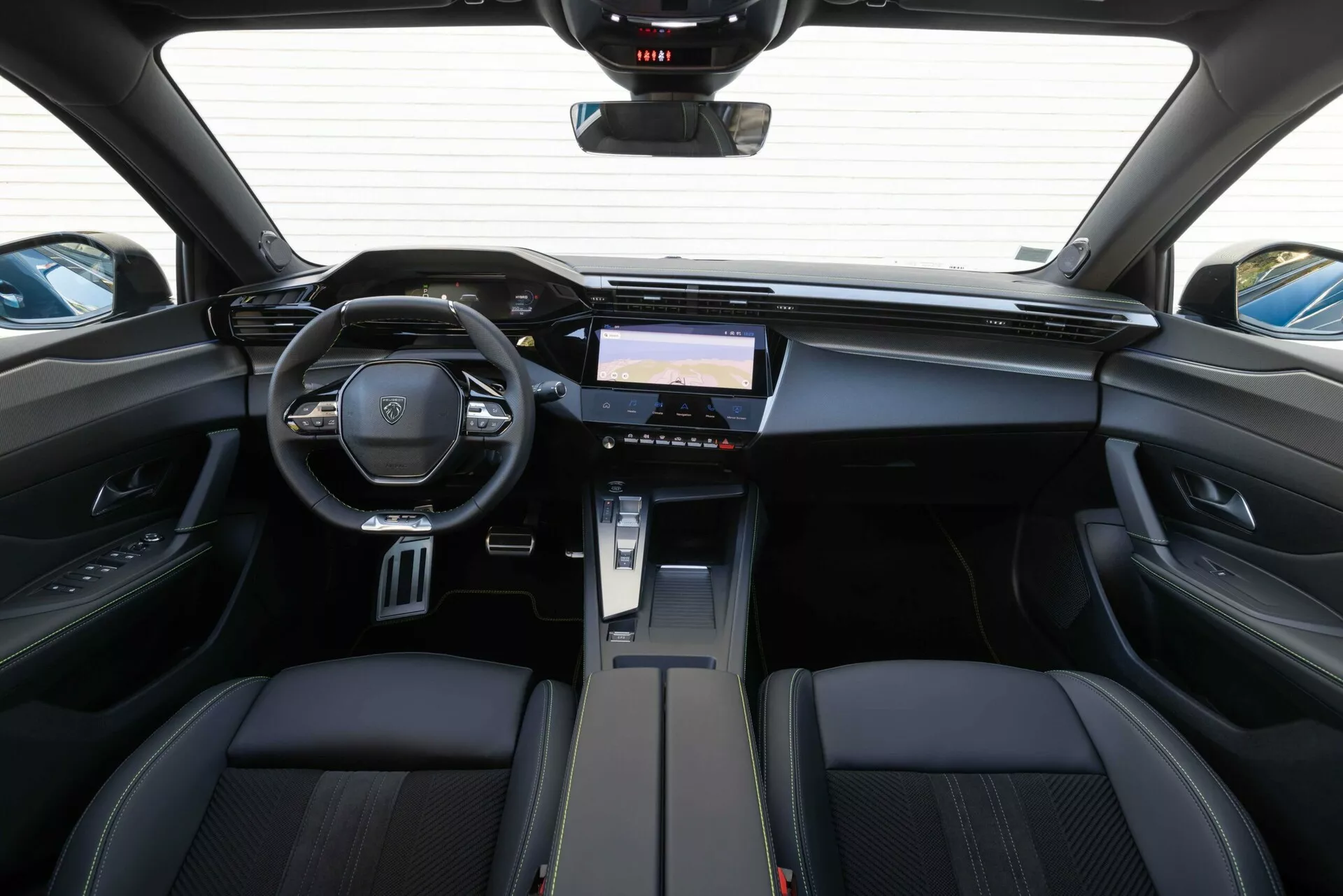 Vue intérieure du Peugeot 408 2023 depuis l'arrière, mettant en avant le tableau de bord, le volant multifonctions avec emblème de la marque et le système d'infodivertissement avancé