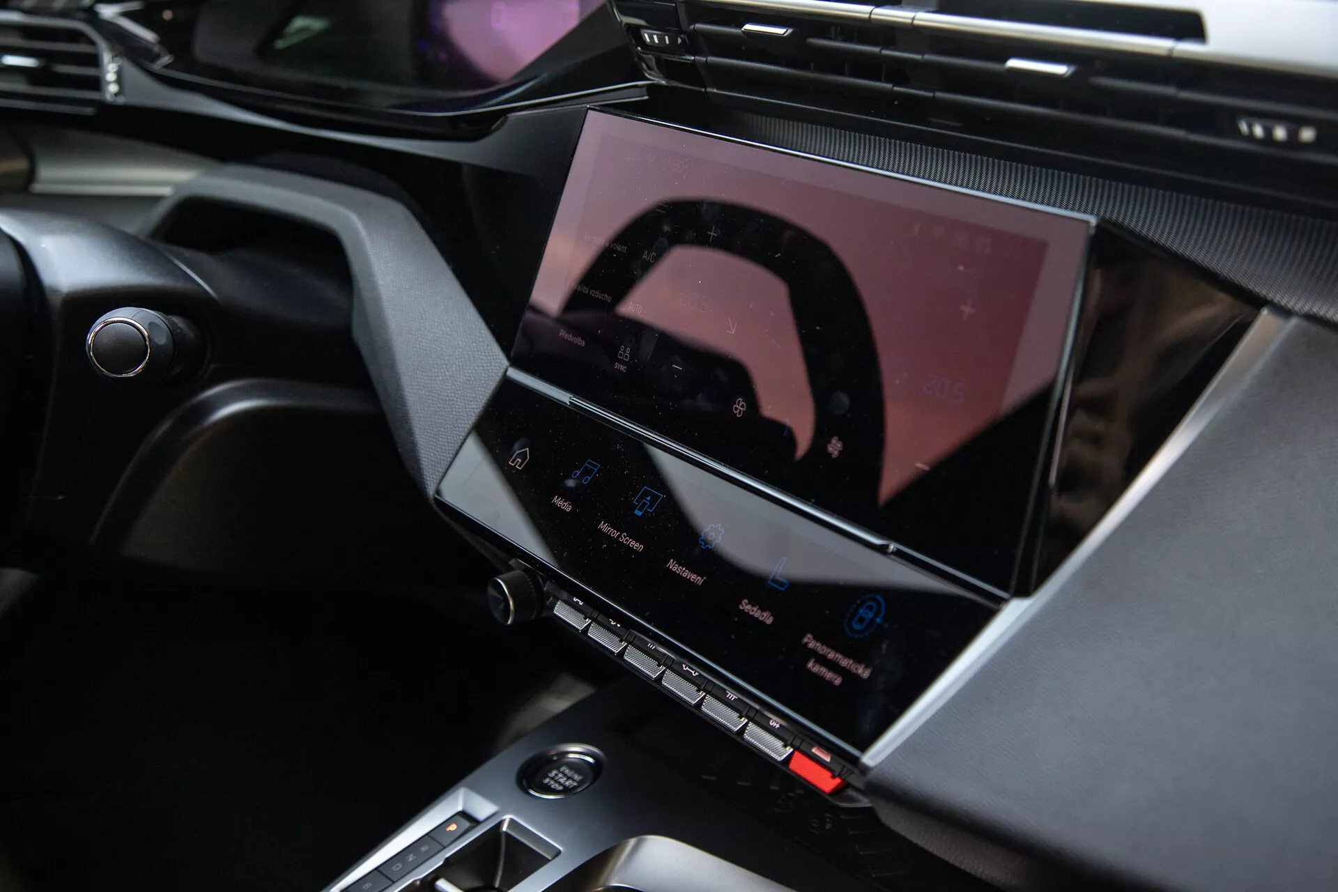 Intérieur de la Peugeot 408 2023 montrant la console centrale et le système d'infodivertissement avancé avec écran tactile, boutons de contrôle du climat et accents de design élégants
