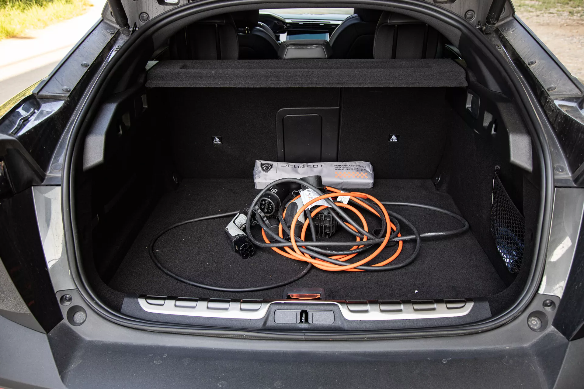 Vue intérieure du coffre de la Peugeot 408 2023 montrant un design spacieux et un câble de chargement pour véhicules électriques, mettant en évidence la technologie EV et la qualité de construction moderne.