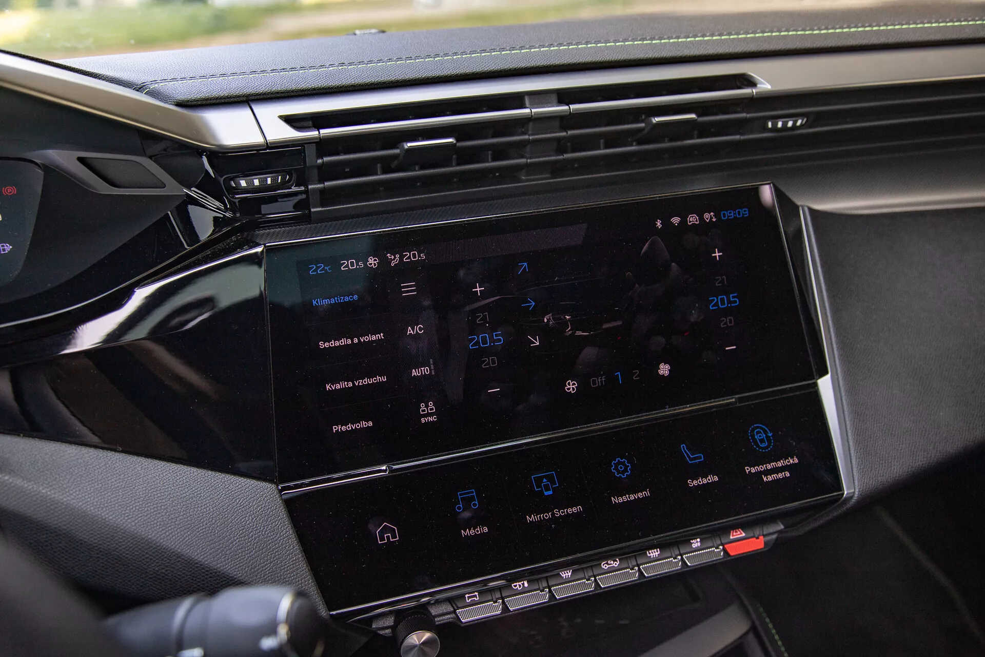 Gros plan sur le système d'infodivertissement de la Peugeot 408 2023 montrant un écran tactile de 8 à 10 pouces avec navigation, réglages du climat, icônes de lecture multimédia et aperçu du tableau de bord, pris du côté passager