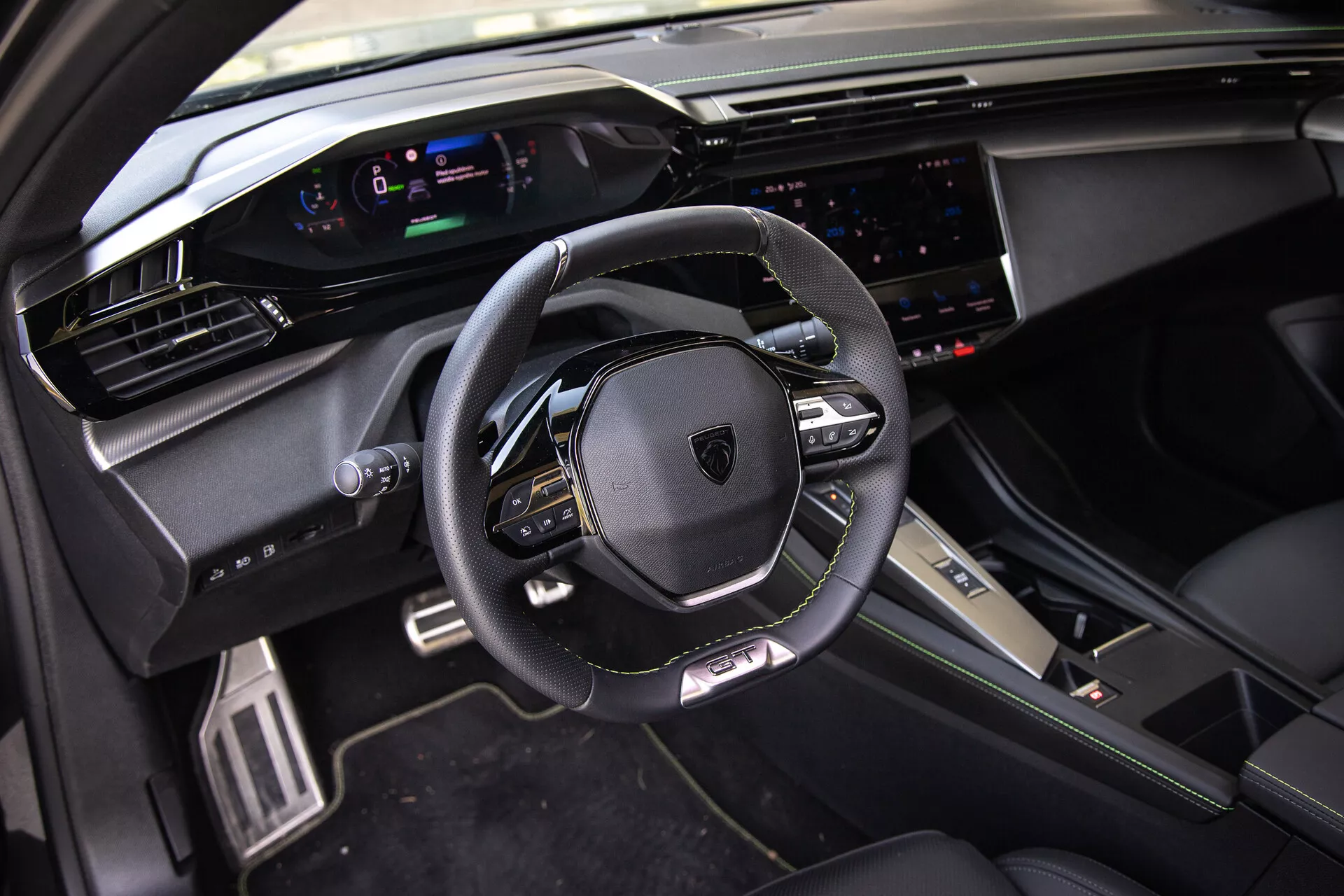 Intérieur du Peugeot 408 2023 présentant un volant multifonctionnel en cuir, un tableau de bord numérique, un système d'infodivertissement tactile large et des éléments de conception sportifs premium sous la lumière naturelle du point de vue du passager avant.