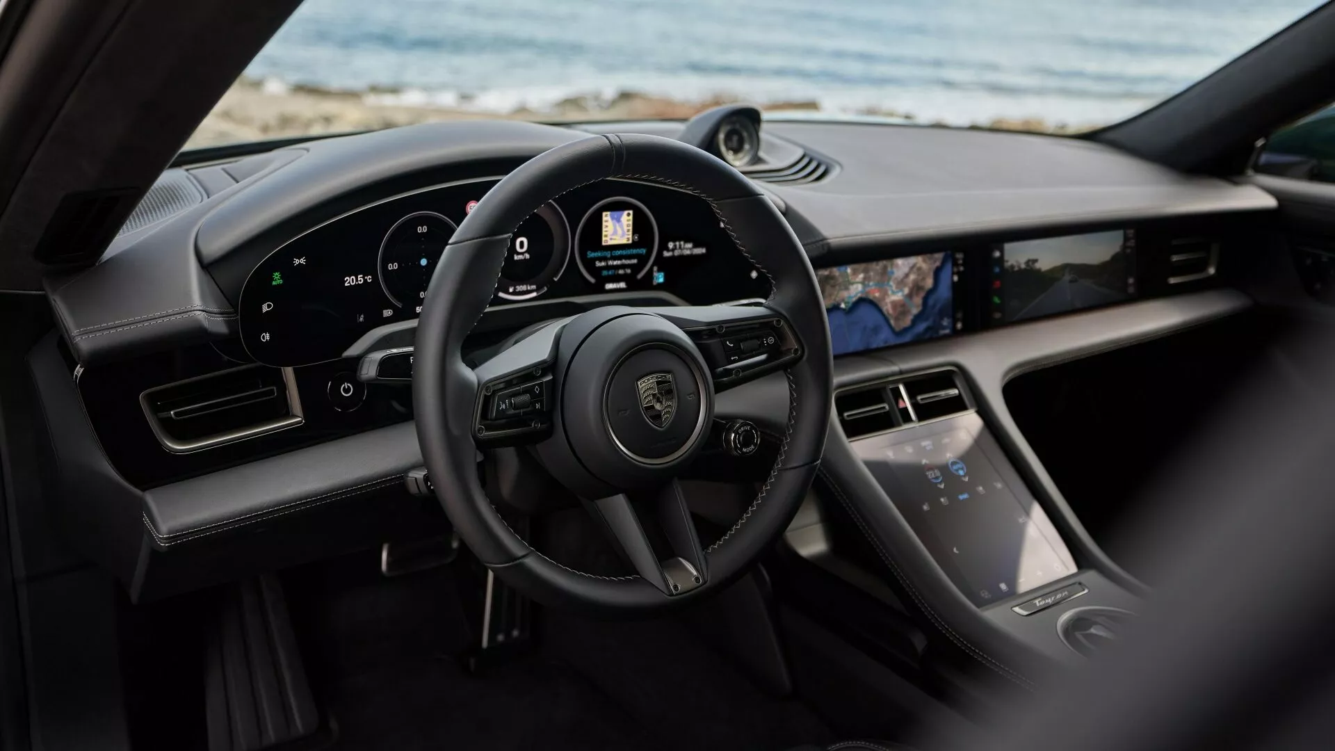 Vue intérieure du Porsche Taycan Y1A restylé 2024 depuis le siège arrière montrant le volant, le tableau de bord numérique et la console centrale avec des fonctionnalités technologiques avancées