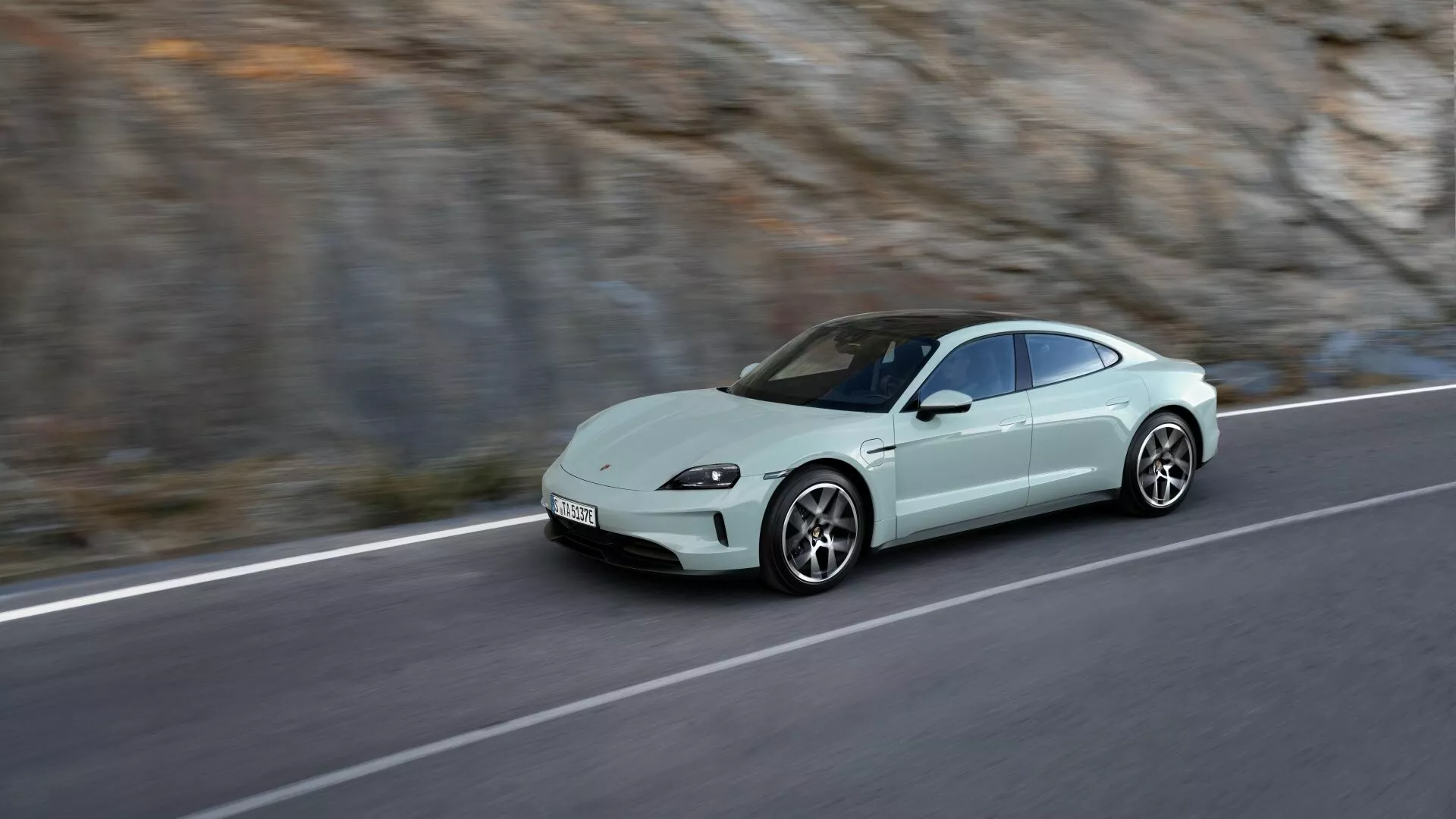 Porsche Taycan Y1A restylée 2024 en mouvement sur une route de montagne, mettant en avant son design coupé aérodynamique, phares LED et allure sportive