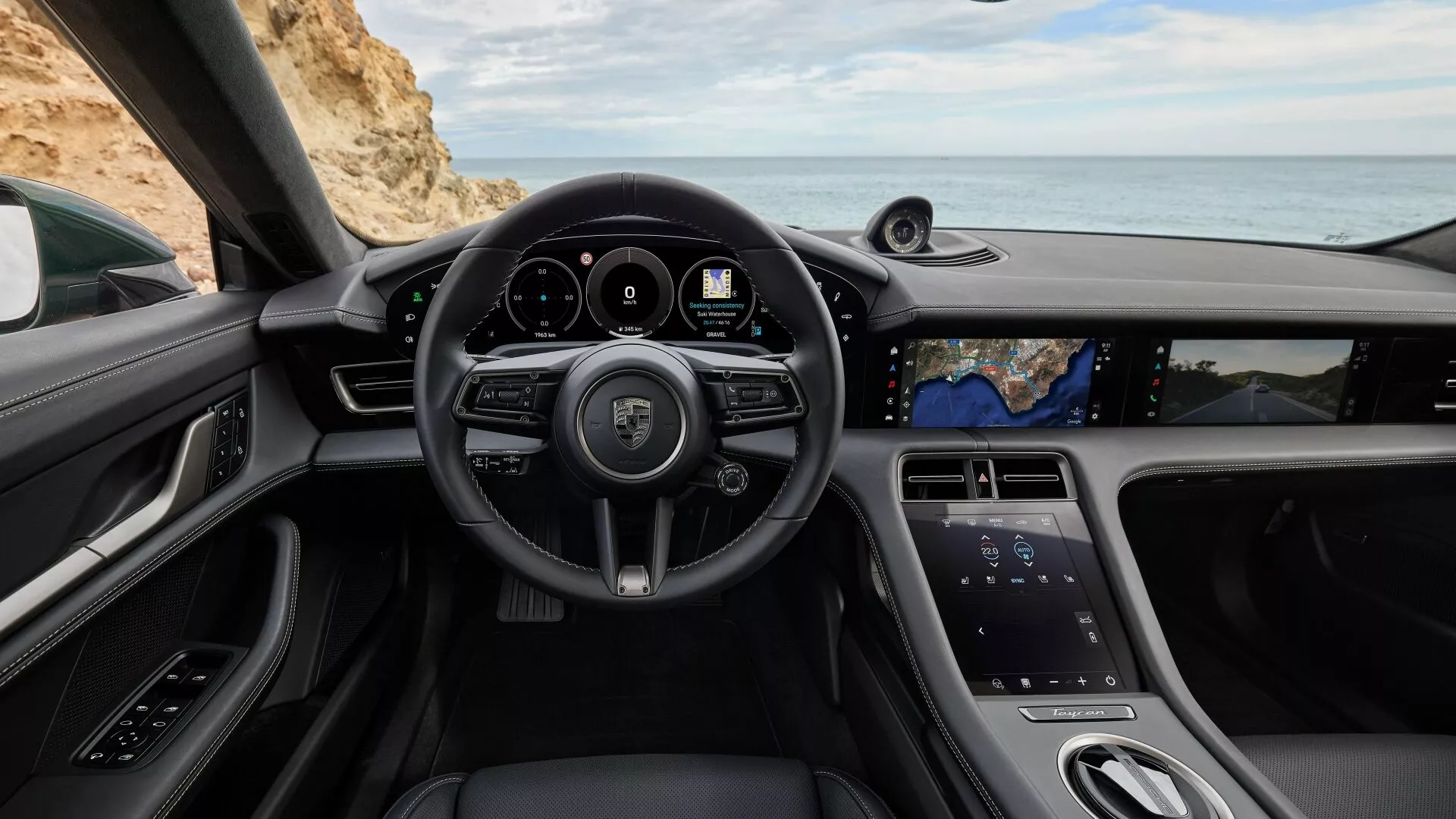 Vue intérieure du Porsche Taycan 2024 Y1A facelift depuis siège conducteur avec volant logotypé, boutons multifonctions, palettes de changement de vitesse, cluster d'instruments numériques, haut-parleur système son premium, vue panoramique du siège passager, écran tactile vertical pour infodivertissement, et design élégant avec finitions en cuir et chrome