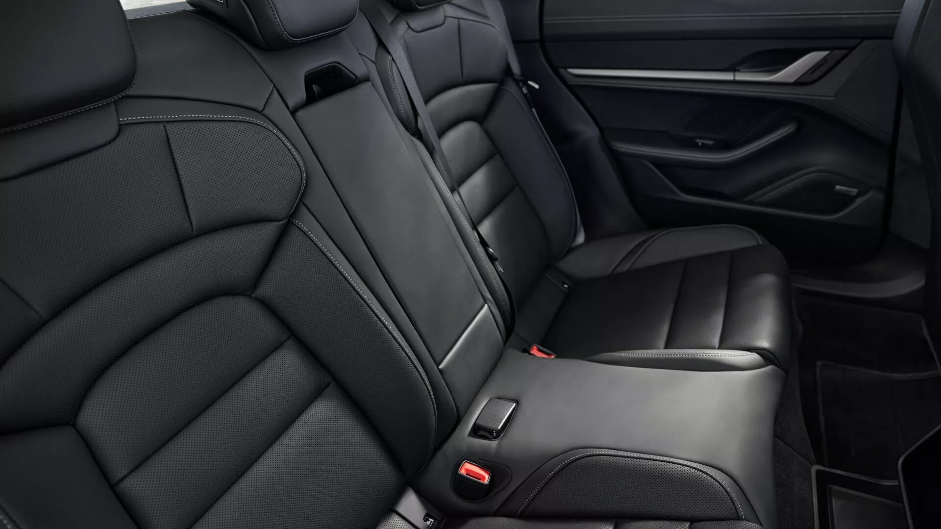 Vue rapprochée des sièges arrières en cuir noir de luxe, accoudoir intégré et design du panneau de porte du Porsche Taycan Y1A facelift 2024, axée sur le confort et les caractéristiques intérieures haut de gamme