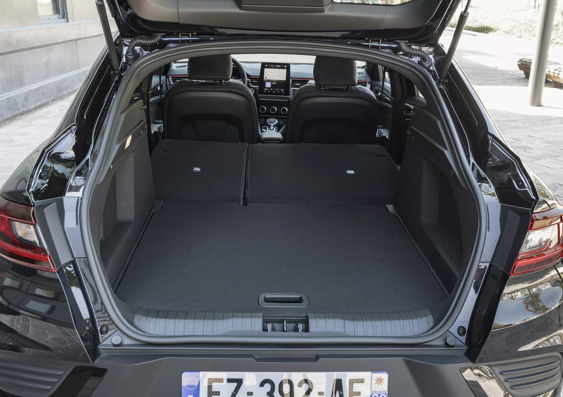 Vue sur l'espace de chargement du Renault Arkana 2021 avec le coffre ouvert, mettant en avant l'intérieur spacieux, les sièges arrière rabattables 60/40 pour augmenter la capacité et les éléments de design arrière modernes sans fonctionnalités technologiques visibles
