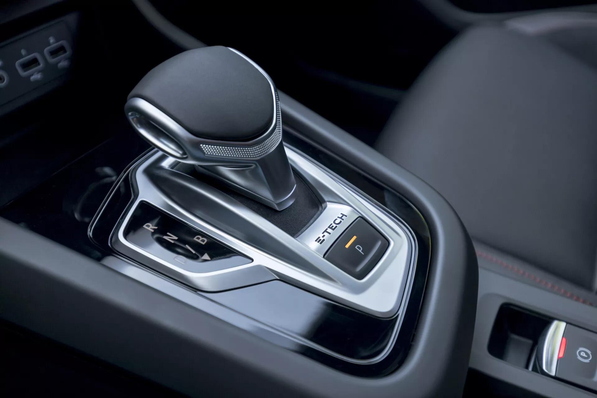 Vue rapprochée du levier de vitesse à transmission automatique de la Renault Arkana 2021 à l'intérieur du véhicule, présentant un design moderne avec un pommeau enveloppé de cuir, des accents chromés et un contrôle du frein de stationnement électronique.