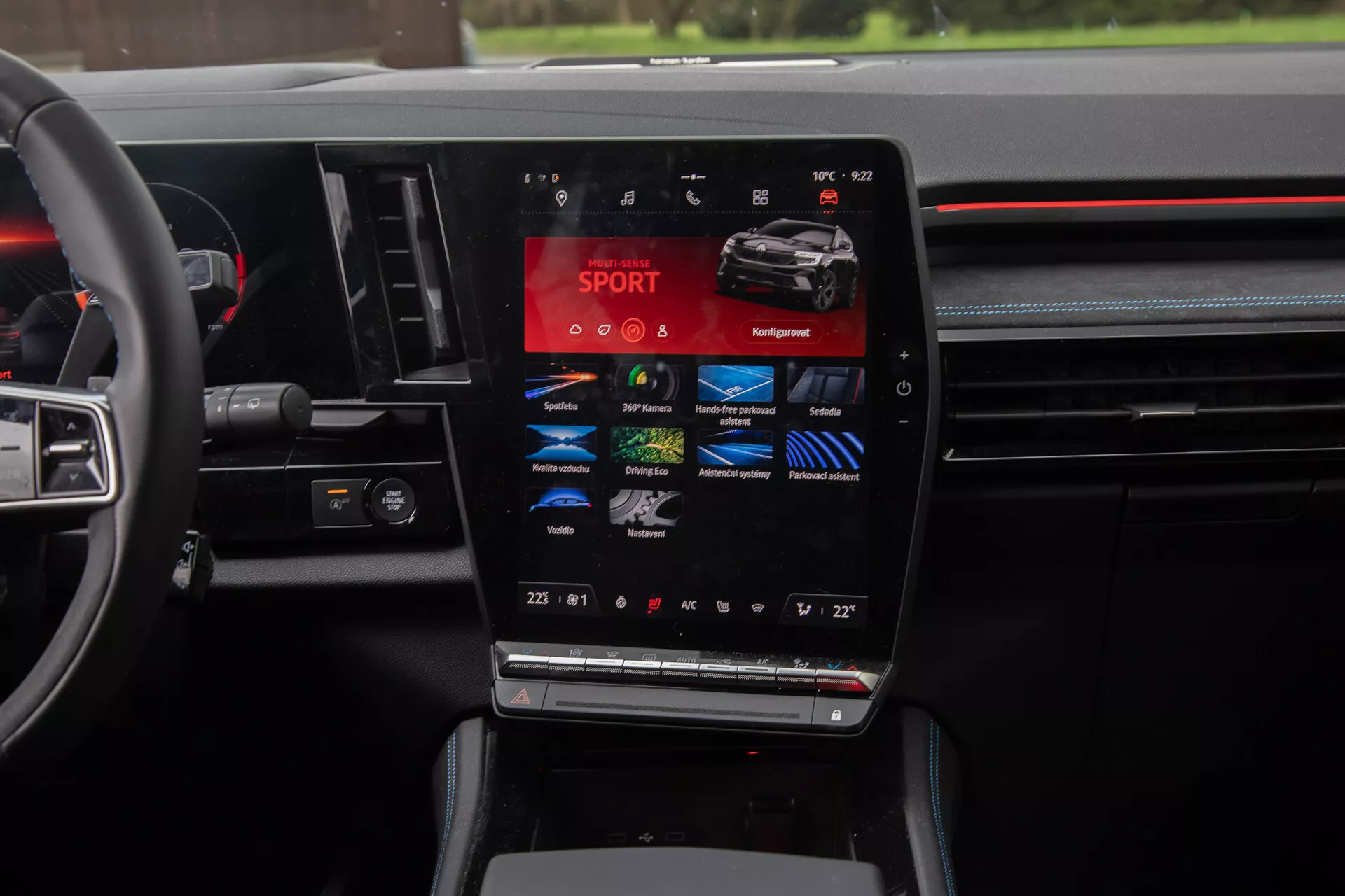 Vue intérieure du Renault Austral 2022 mettant en avant la console centrale avec un grand écran tactile vertical affichant des modes de conduite tels que SPORT, Confort, Éco, avec réglages de climatisation bi-zone et commandes multifonctions au volant, encapsulant l'essence de la technologie automobile moderne et du design de luxe.