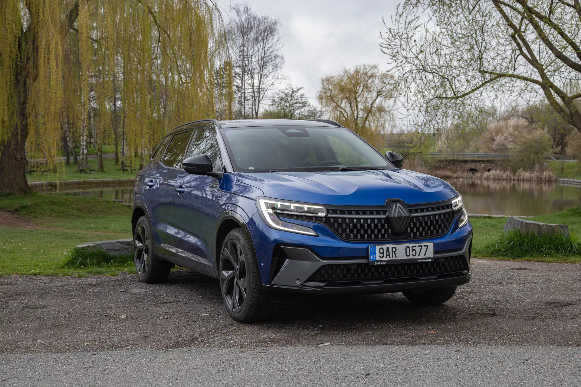 SUV bleu Renault Austral 2022 garé en extérieur montrant la façade avant et le côté conducteur avec phares LED, pare-chocs sportif et roues en alliage sur un arrière-plan naturel