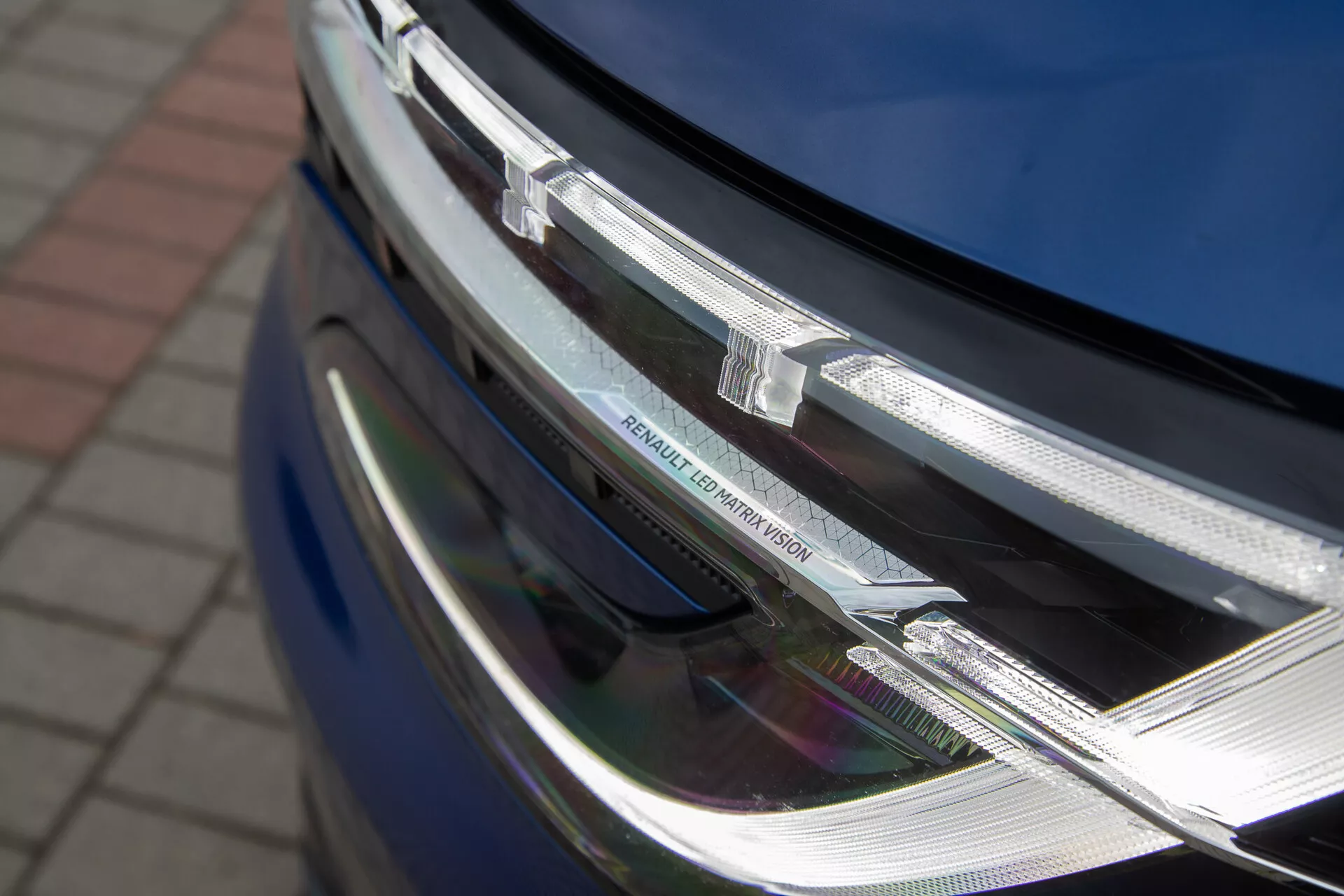 Vue rapprochée de la section avant du Renault Austral 2022 montrant le phare LED et l'assemblage de calandre chromée avec le badge du fabricant, soulignant son design moderne et sa technologie d'éclairage sophistiquée.
