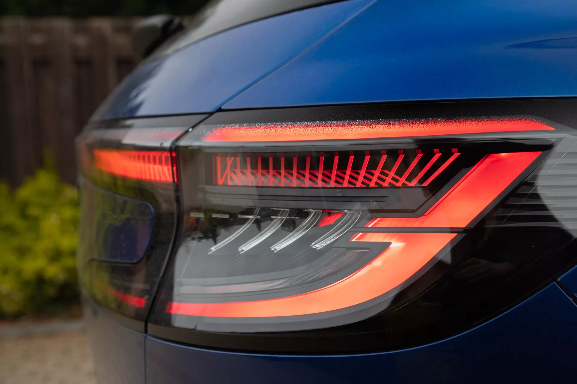 Gros plan sur le feu arrière élégant de la Renault Austral 2022 sous un angle trois quarts, présentant des éléments LED horizontaux pour les fonctions de freinage et de marche arrière, axé sur le design moderne et l'efficacité énergétique.