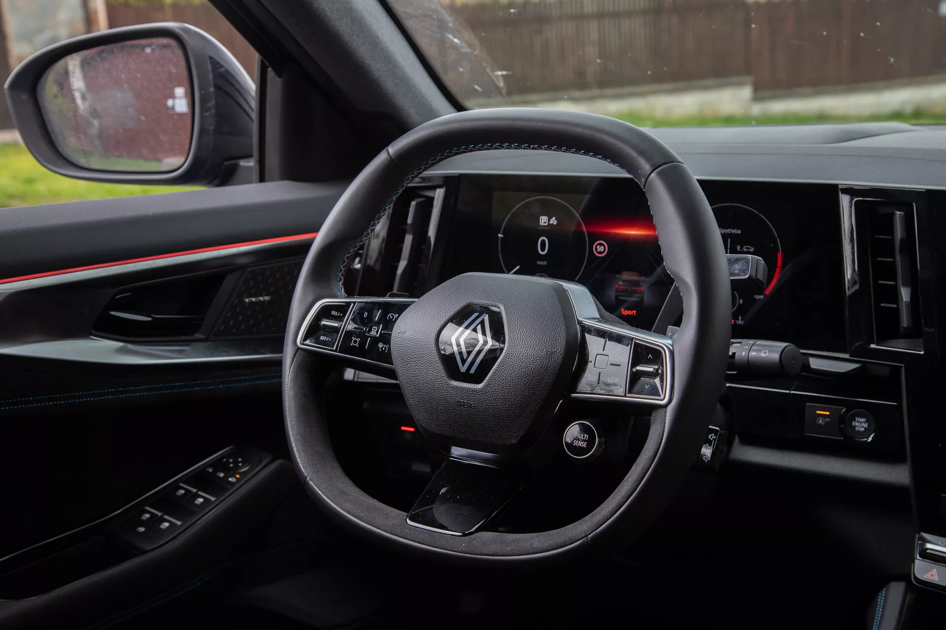 Photo de l'intérieur du Renault Austral 2022 depuis la perspective du conducteur montrant le volant avec commandes intégrées, tableau de bord numérique et partie de la console centrale.