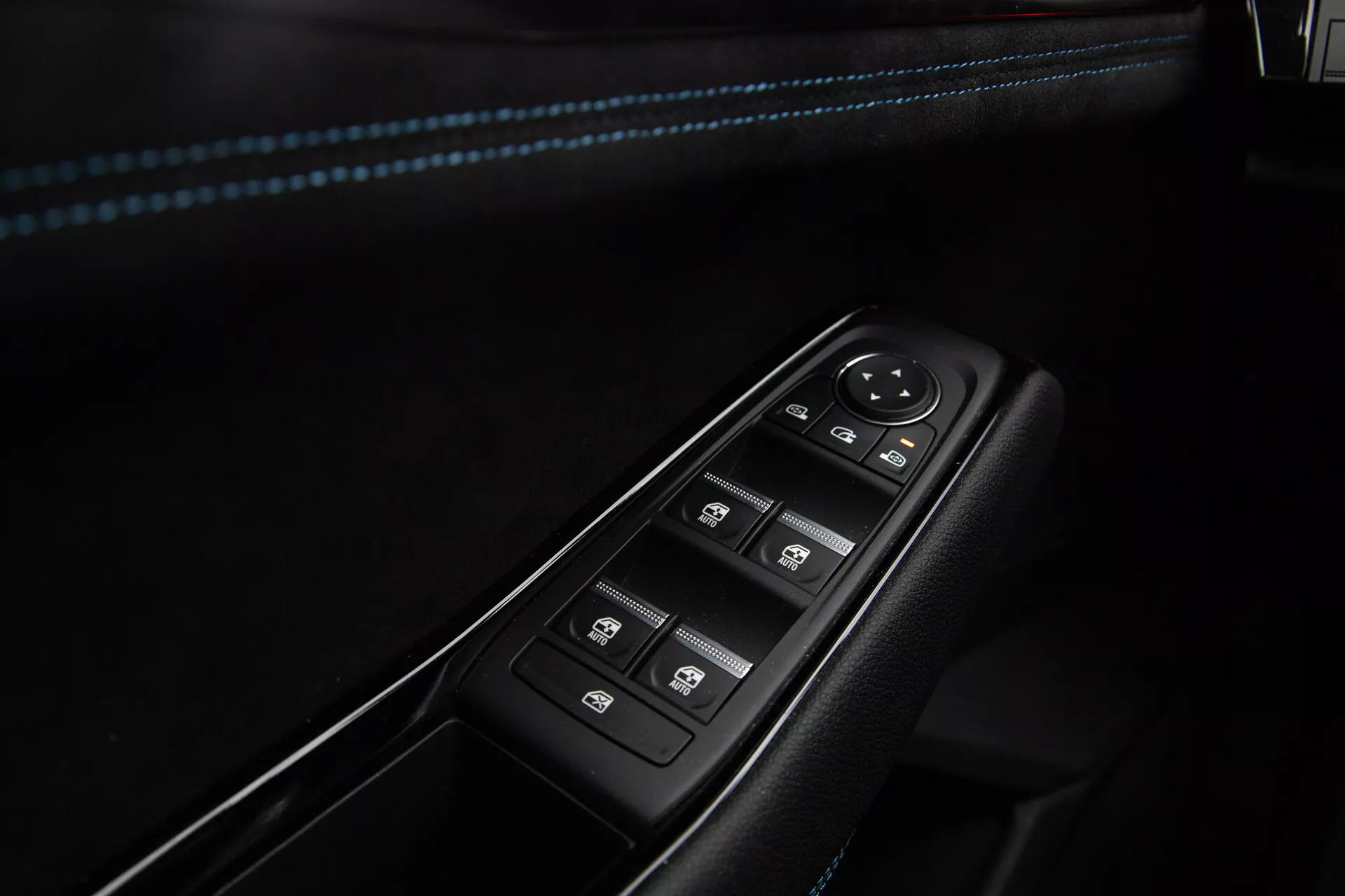 Gros plan sur les commandes de porte côté conducteur du Renault Austral 2022, présentant des boutons pour le réglage électrique des fenêtres avec opération à une touche, un cadran pour le réglage électronique des rétroviseurs latéraux et un interrupteur de verrouillage central, le tout enchâssé dans un panneau noir bordé de chrome et avec des coutures d'accent bleu sur l'accoudoir.