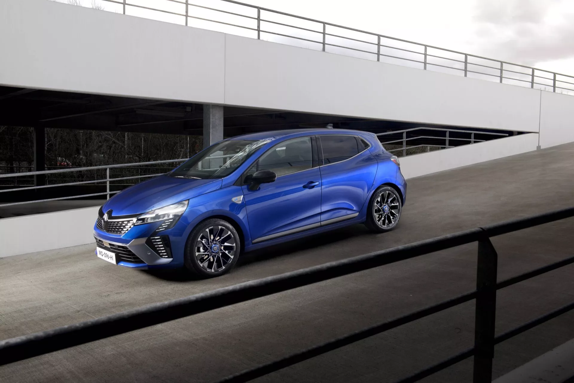 Hatchback moderne Renault Clio (V facelift) 2023 sur parking, montrant calandre chromée, phares LED, jantes alliage sportives et peinture métallisée sous un angle avant de trois quarts
