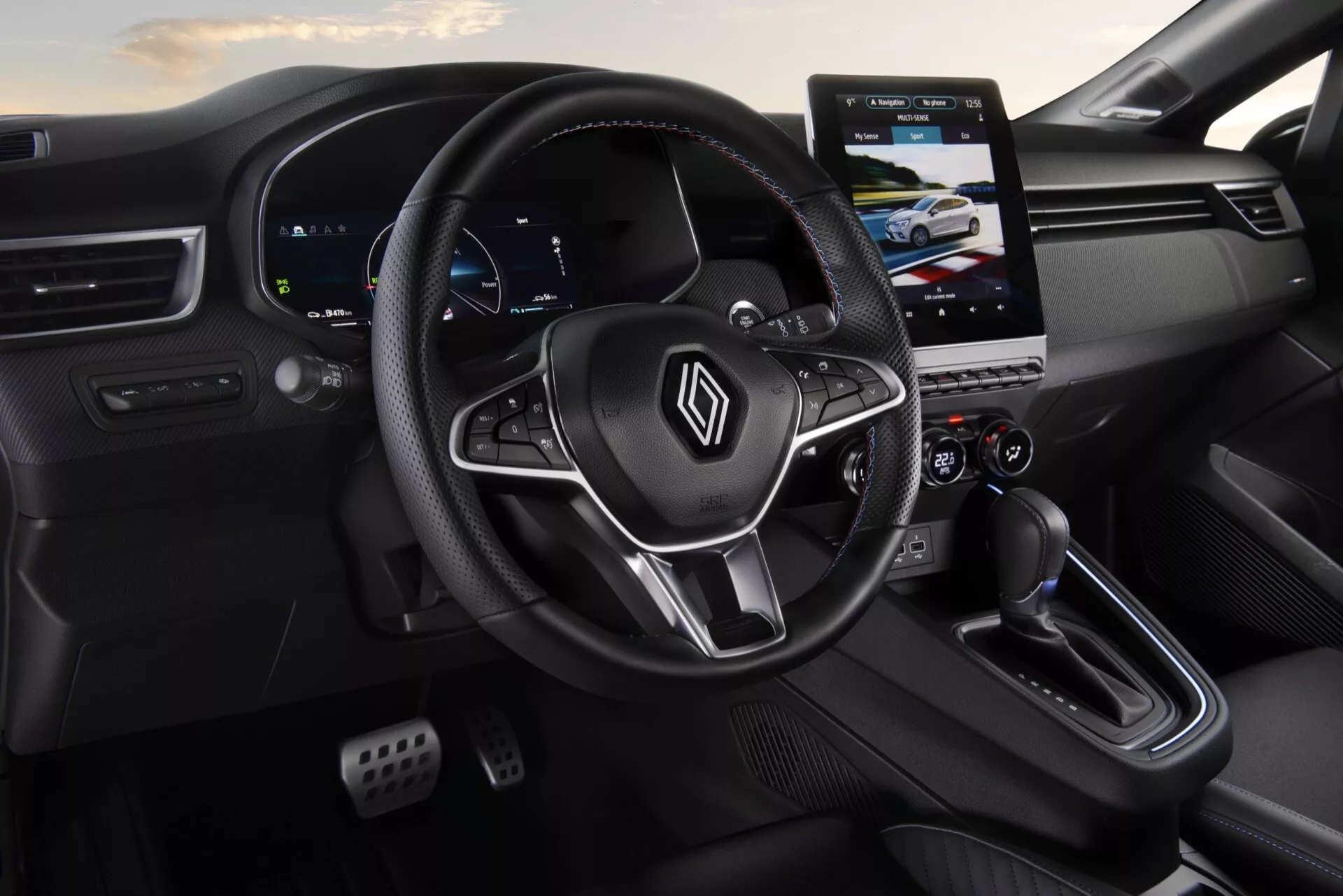 Vue intérieure de la Renault Clio V-facelift 2023 mettant en évidence le volant emballé en cuir avec commandes, le tableau de bord numérique, le système d'infodivertissement tactile et le contrôle climatique à double zone du point de vue du conducteur