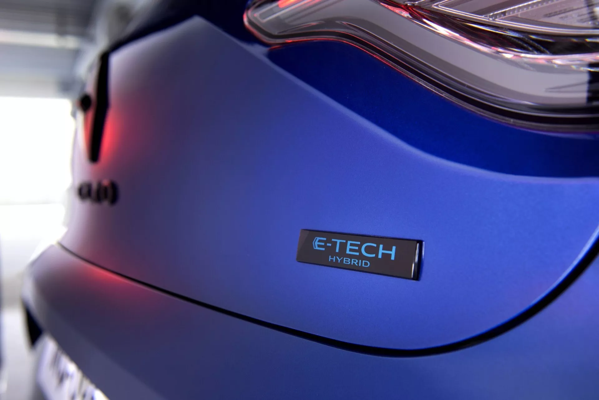 Vue rapprochée du Renault Clio V-Facelift 2023 présentant le panneau arrière, l'insigne E-TECH HYBRID et la peinture bleu métallique