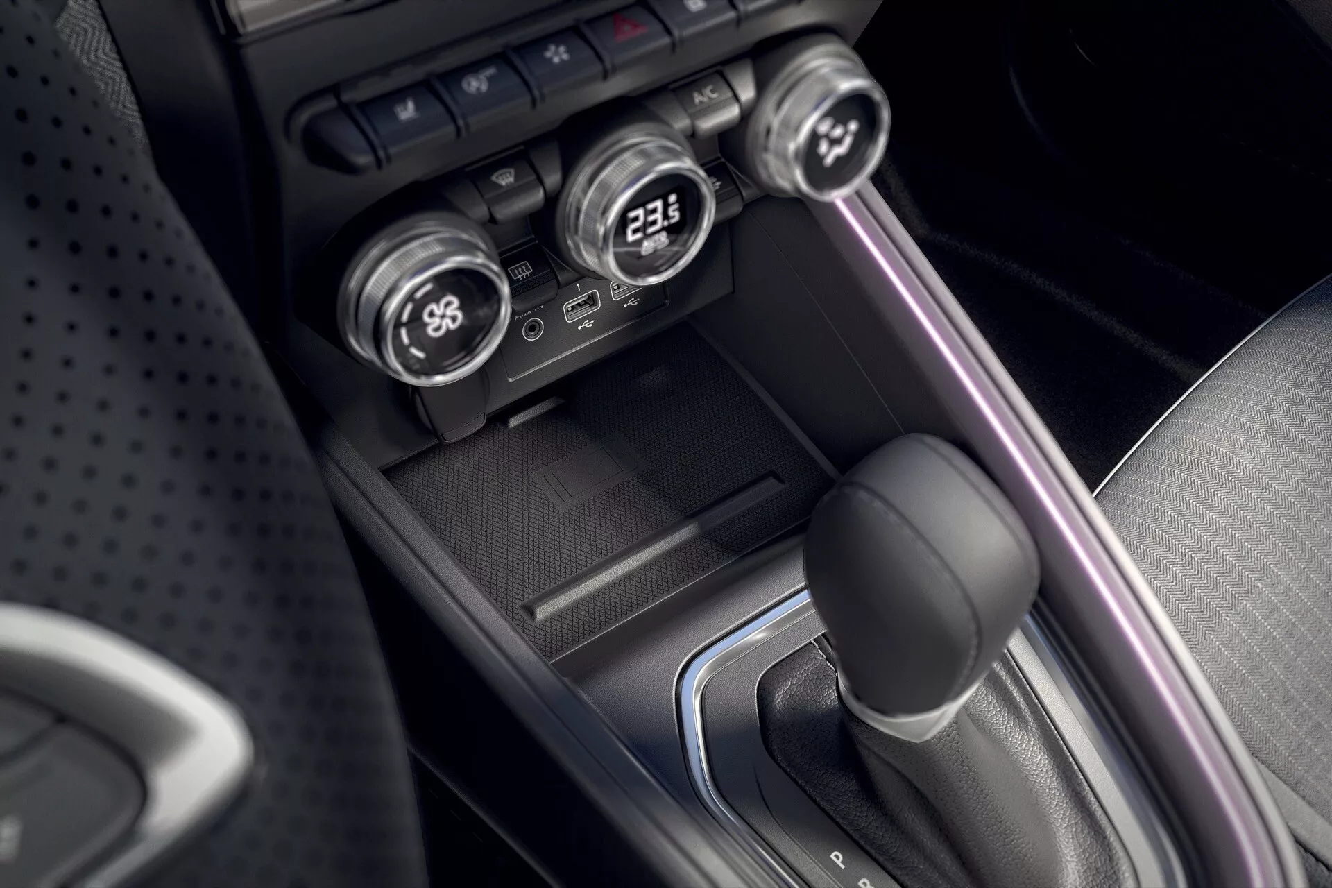 Vue détaillée de la console centrale du Renault Clio V-facelift 2023 présentant un levier de vitesse automatique avec un soufflet en cuir, des cadrans de contrôle climatique bi-zone et une esthétique de design moderne