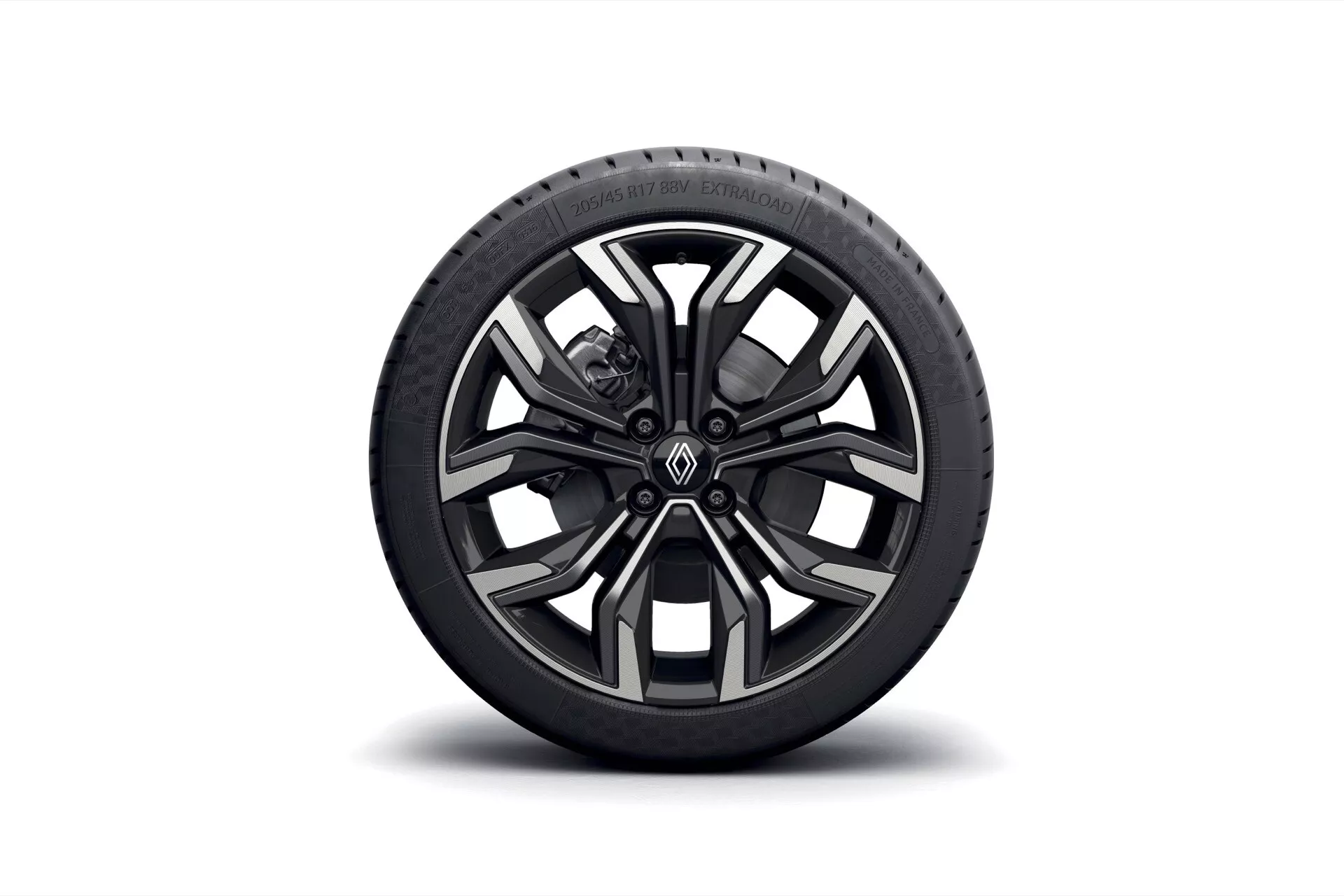 Détail d'une seule roue de Renault Clio V-facelift 2023 montrant une jante en alliage multibranches noire et usinée et un pneu avec le nom du fabricant et les spécifications visibles sur un fond blanc