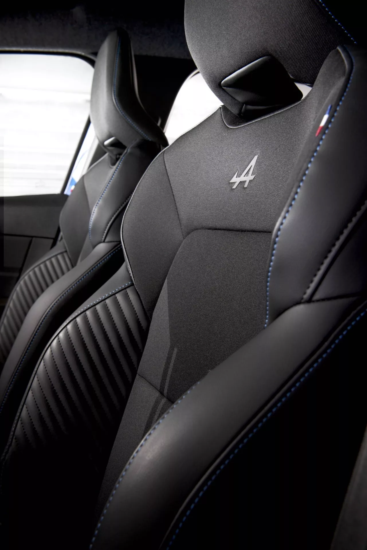 Gros plan de l'intérieur du Renault Clio V-facelift 2023 montrant les sièges baquets sport avant avec une sellerie en cuir noir de haute qualité, des coutures distinctives et un emblème d'édition spéciale