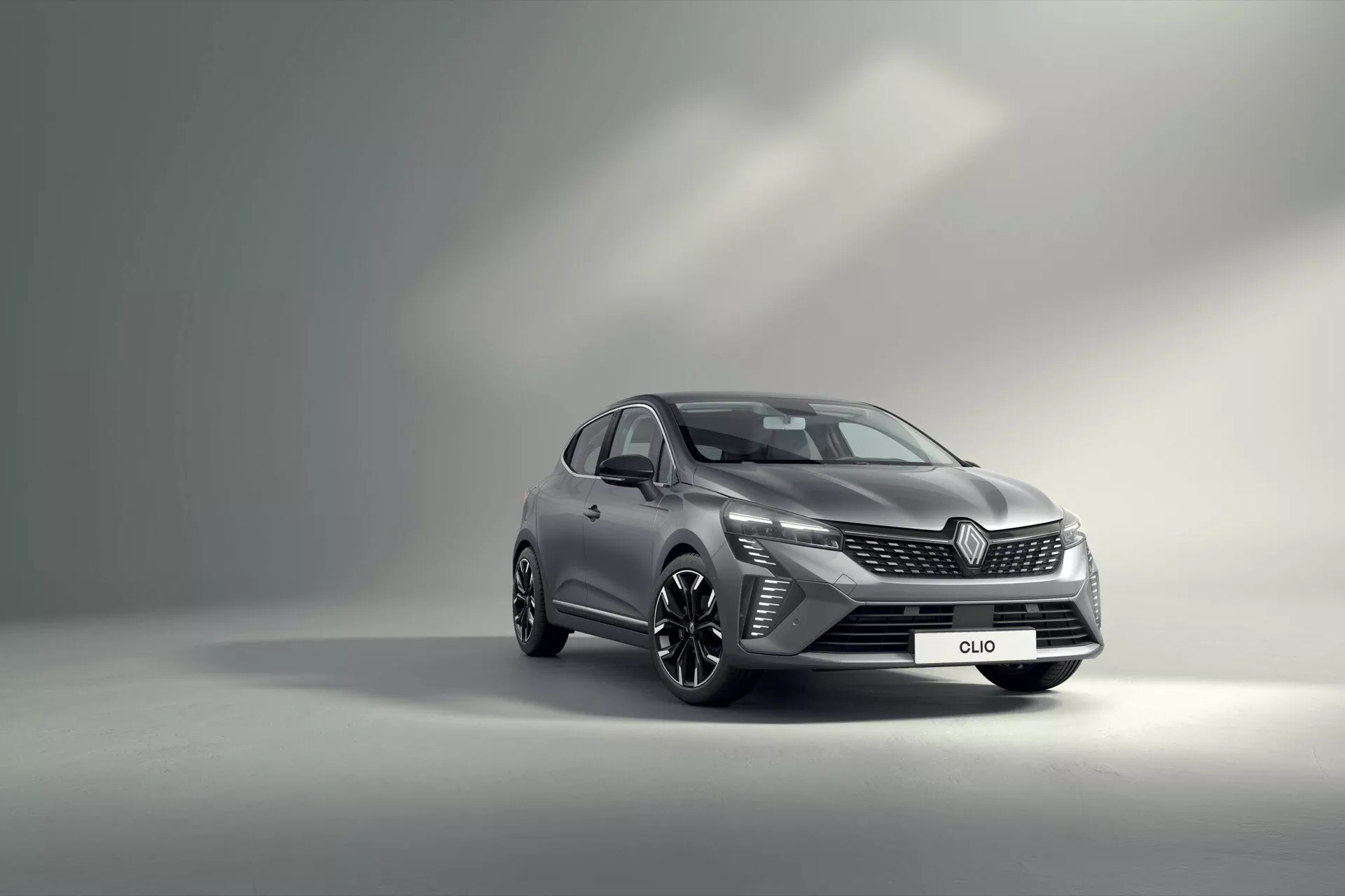 Renault Clio V-facelift 2023 mettant en avant son design dynamique avec une vue de trois quarts avant contre un fond de studio dégradé, soulignant les phares LED, la grille avant raffinée, les jantes en alliage sportives et les indicateurs intégrés dans les rétroviseurs latéraux.