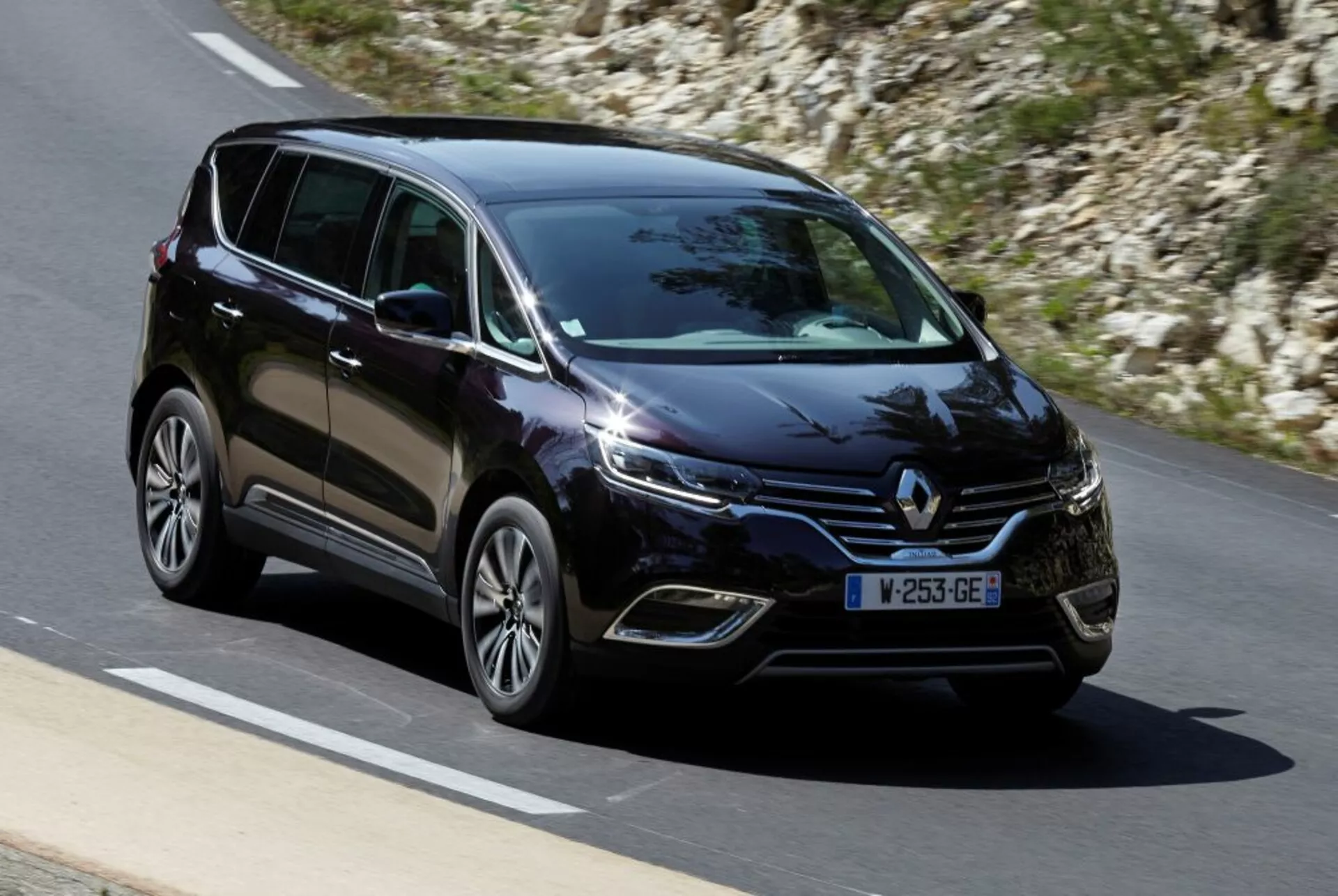 Minivan Renault Espace 2015 en mouvement sur route pavée, vue de trois quarts avant montrant les phares LED, les roues en alliage et les caractéristiques du design moderne
